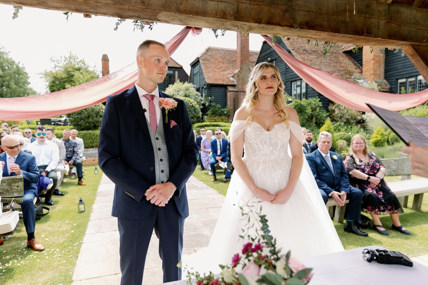 An elegant outdoor wedding celebration with guests and the wedding party dancing and mingling in a garden setting.