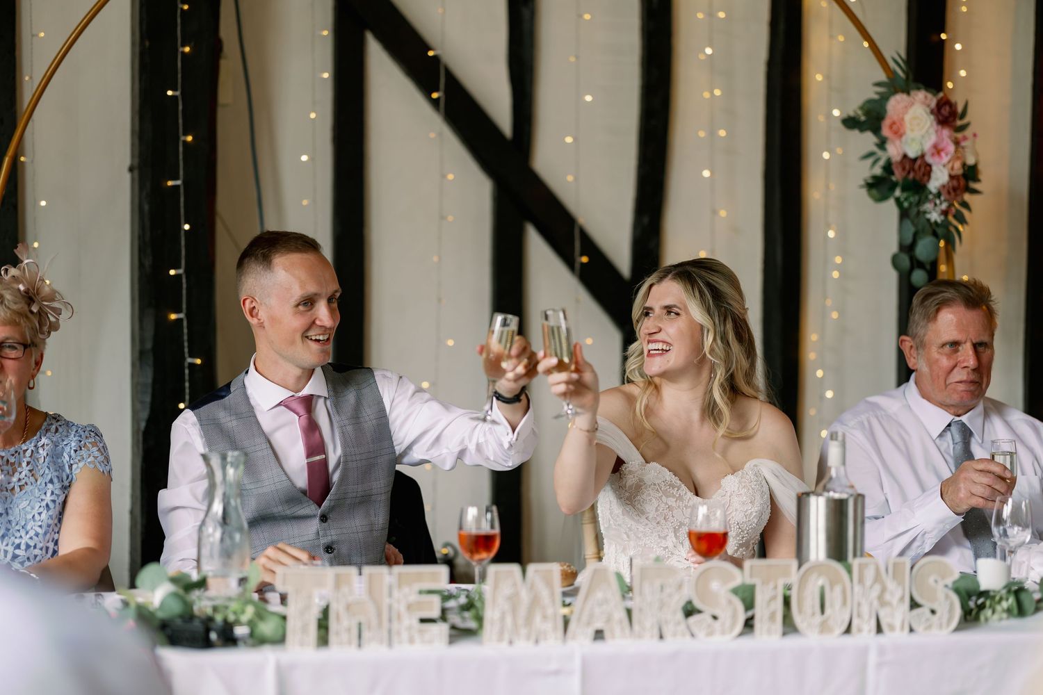 Wedding guests sitting at long white dining tables during a reception celebration.