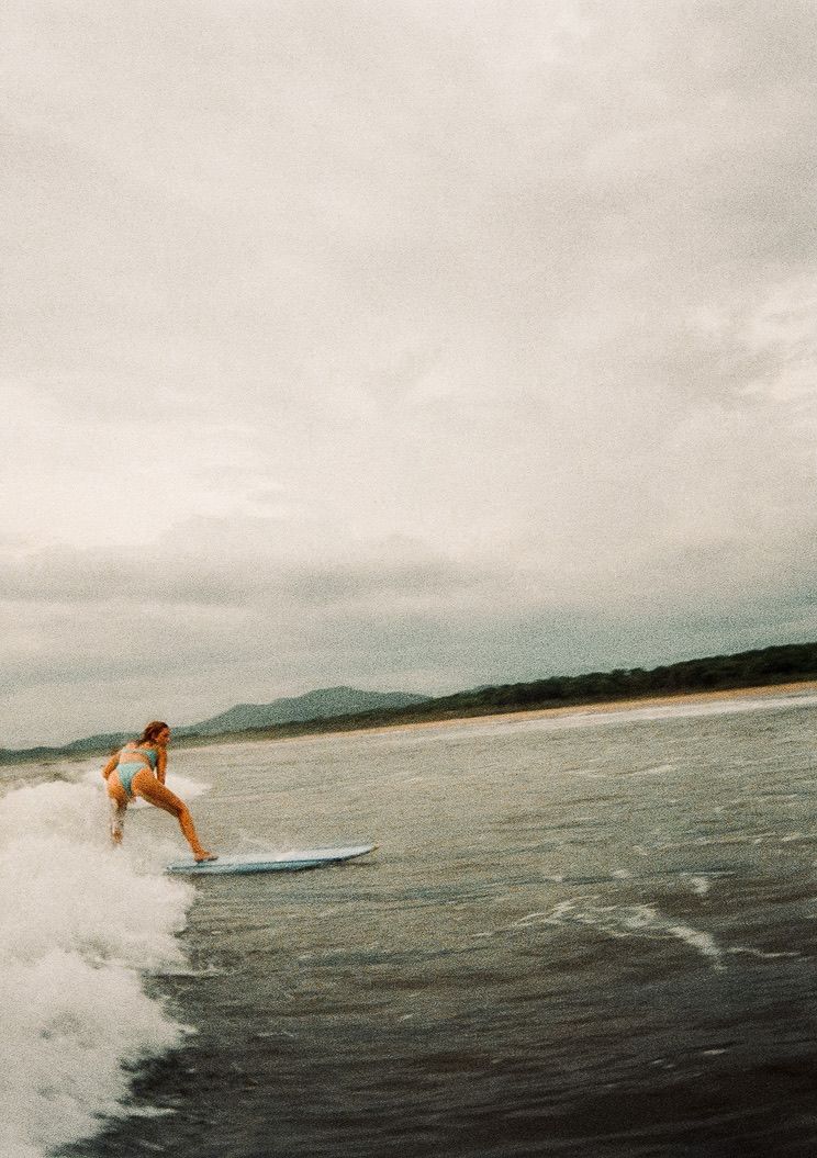 Travel photographer Athena Arnold surfing down a wave in Costa Rica.