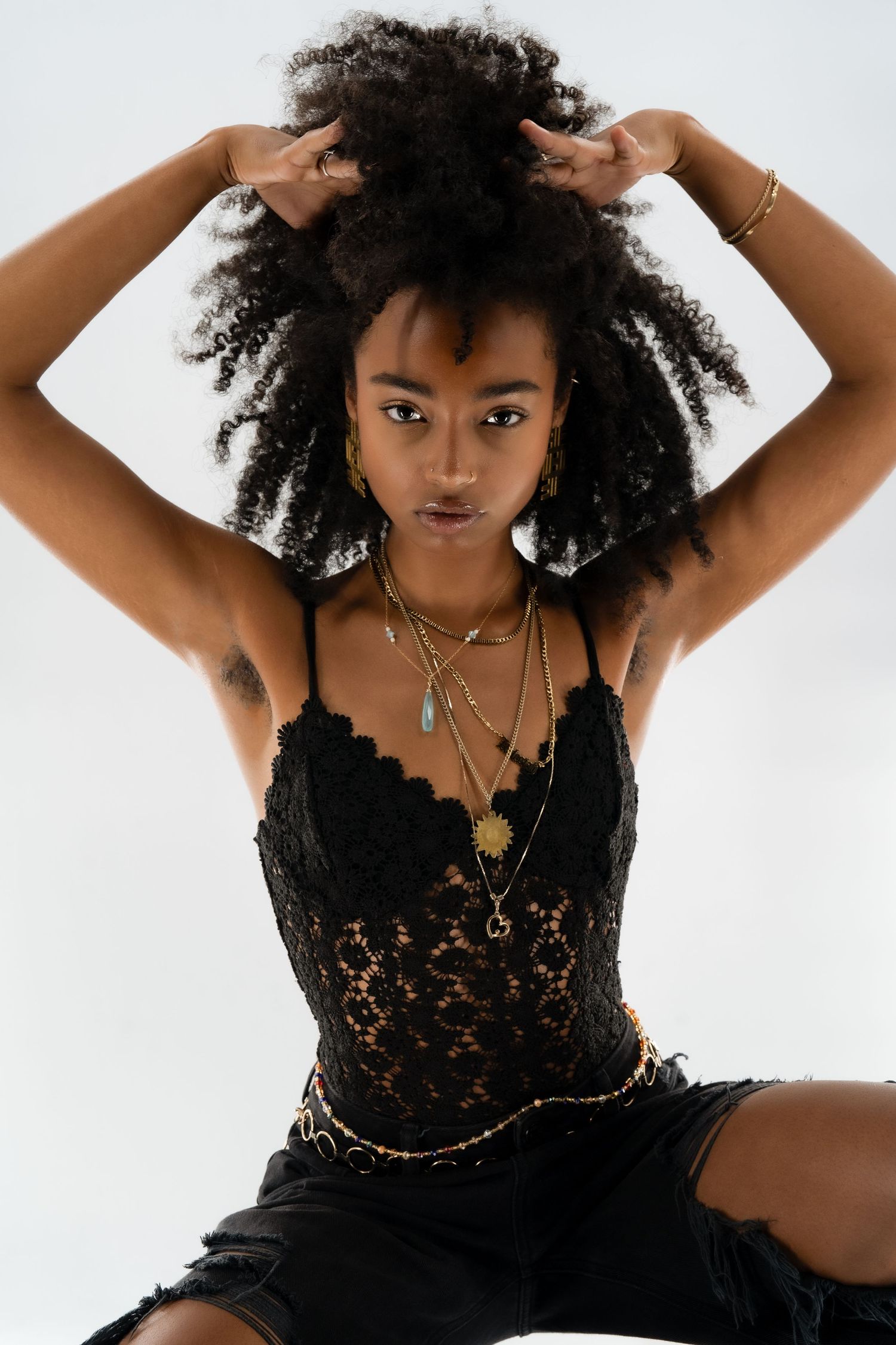 Artistic portrait showcasing natural hair and black lace outfit with gold jewelry.