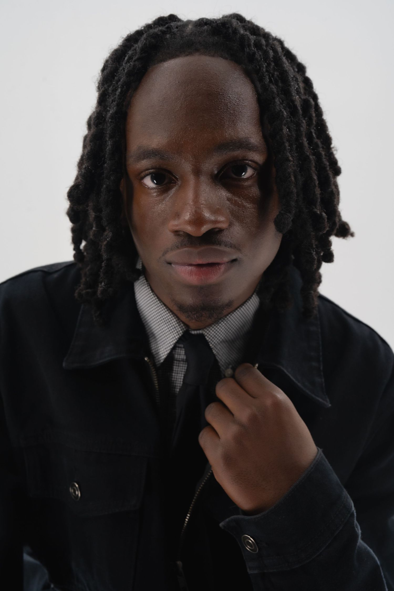 Close-up fashion portrait showing details of a black jacket, white collar and black tie.
