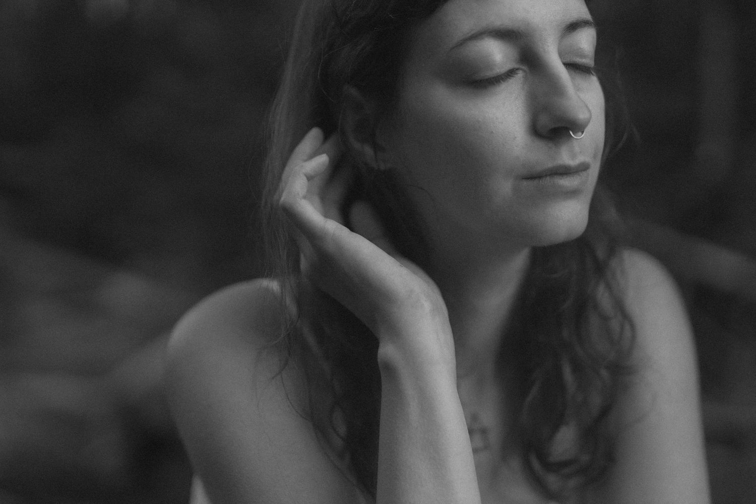 woman with a calm expression tucks her hair behind her ears during self love session