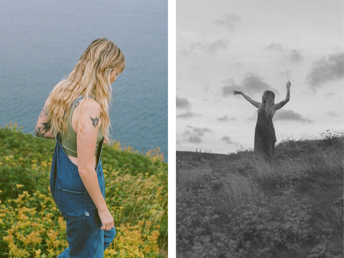 blonde woman with tattoos walks through a field of yellow wildflowers by the ocean