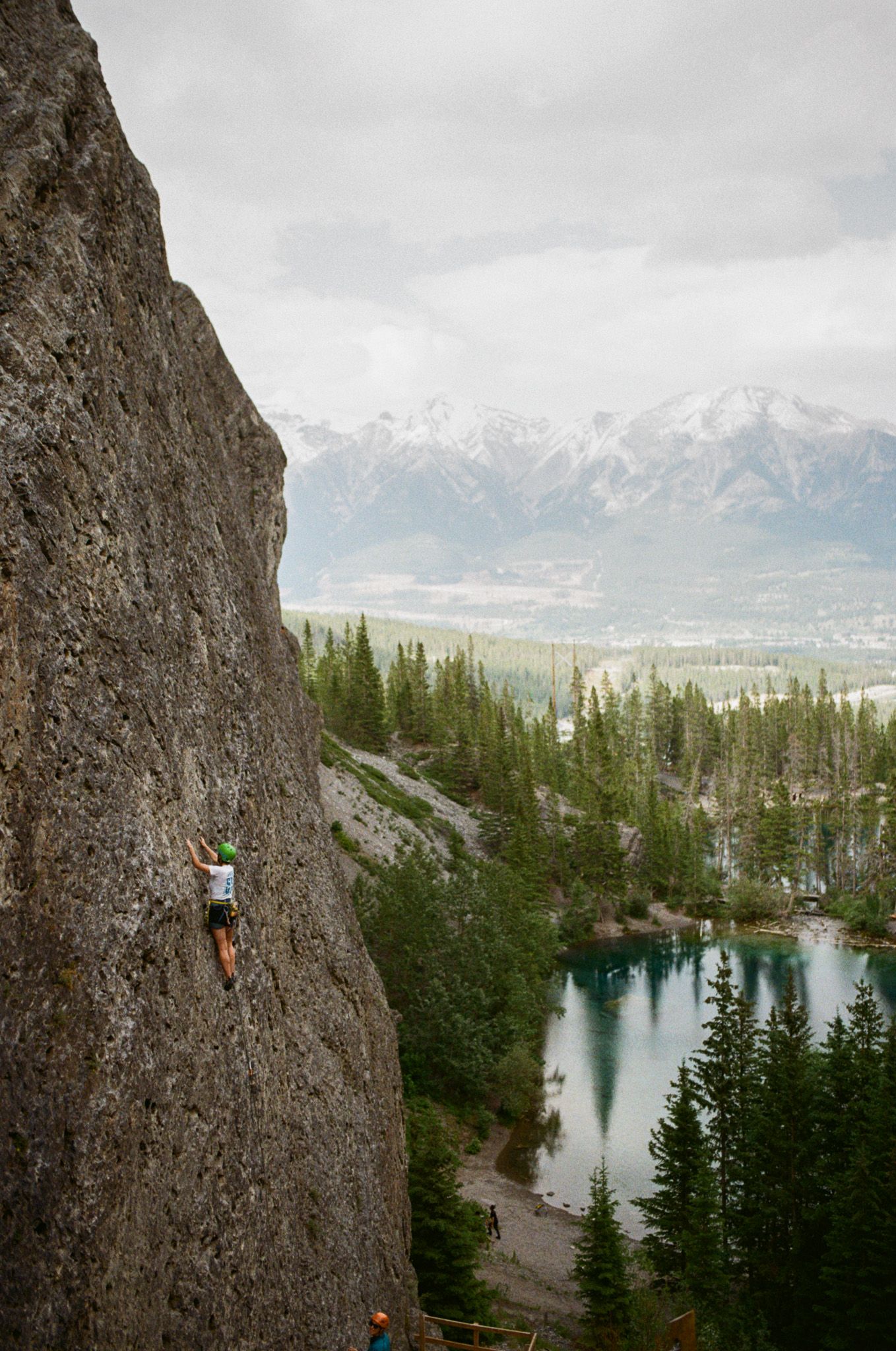 Banff Elopement Photographer Heather Nolan is rock climbing  halfway up the rock face at Grassi Lakes in Kananaskis