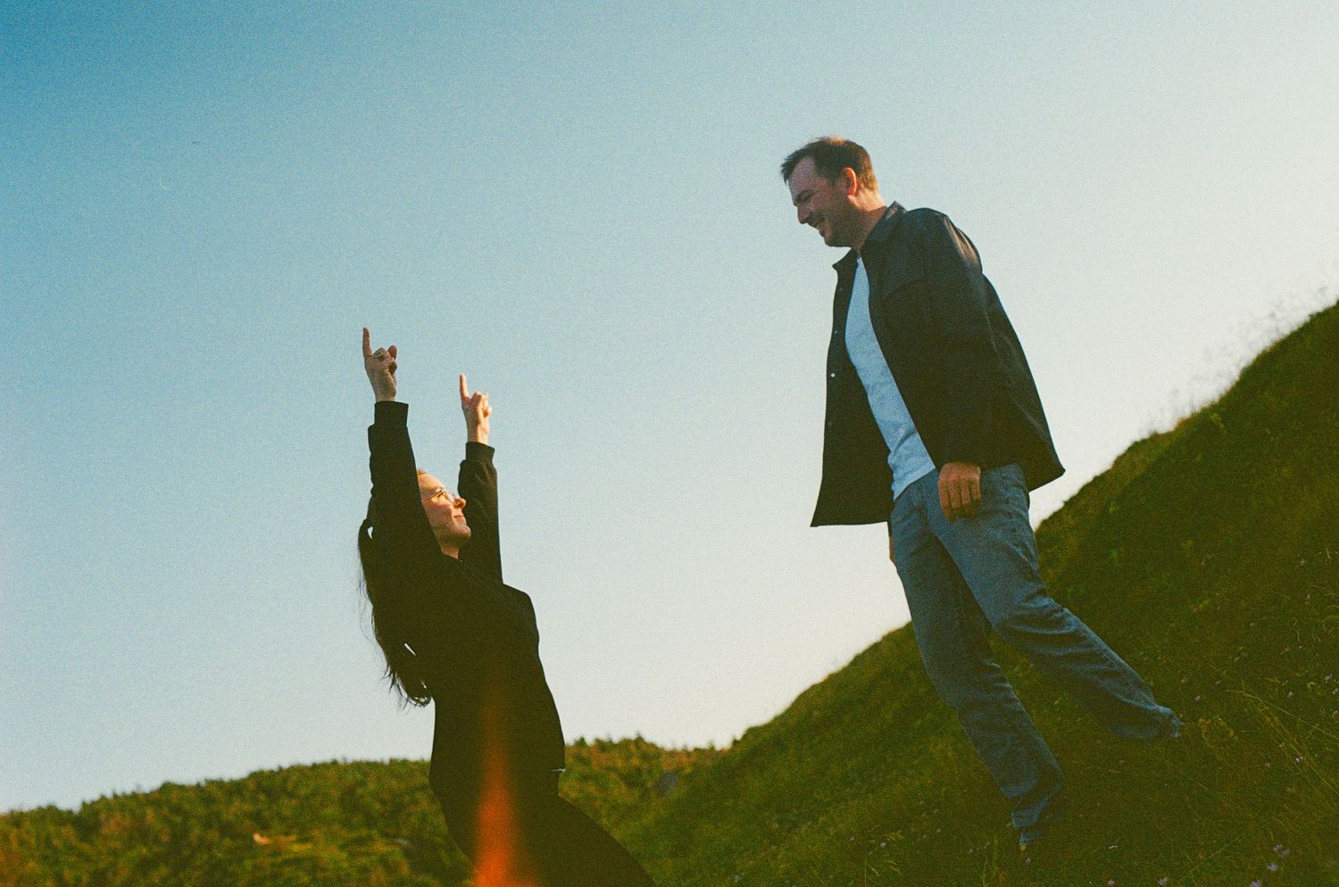 35 mm film photo of a couple playfully chasing each other at golden hour