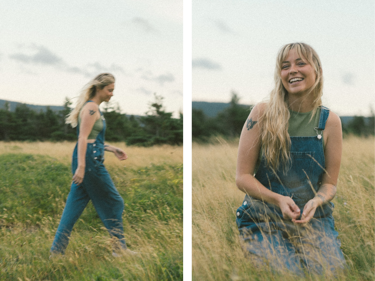 blonde woman with tattoos laughs in a field of tall grass at sunset