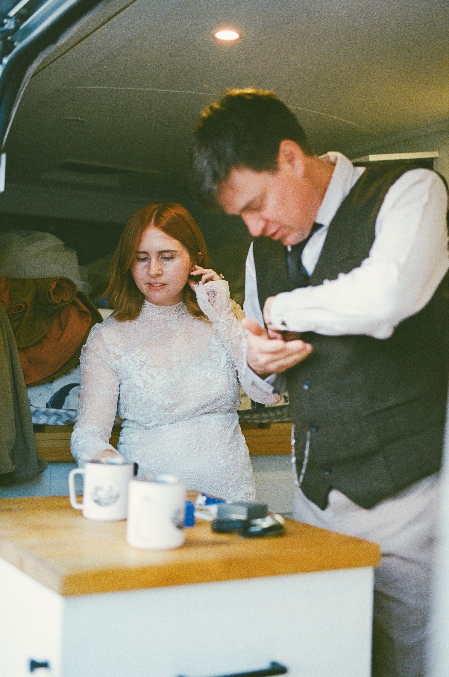 35 mm film photo of bride and groom getting ready for their elopement in their camper van with coffee