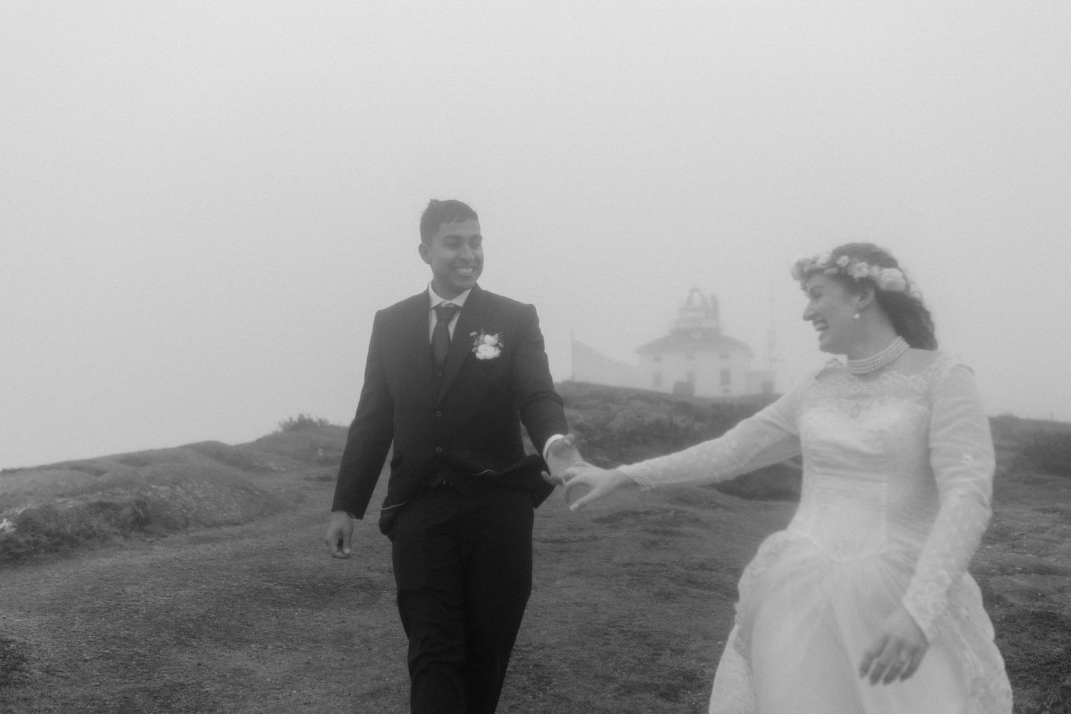 bride and groom hold hands and laugh in the fog by the Ucluelet lighthouse during their Vancouver Island elopement