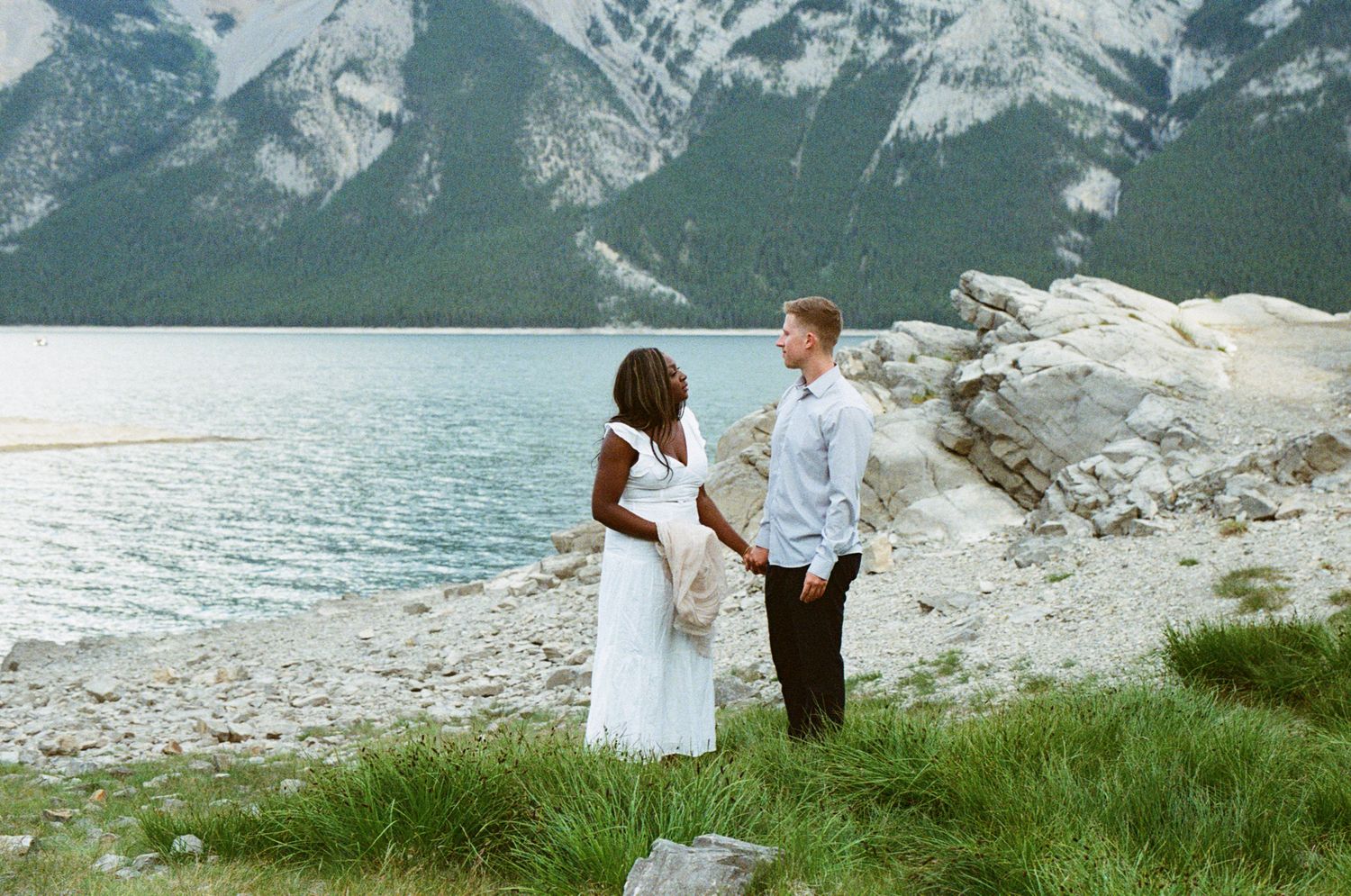 35 mm film photo of bride and groom sharing an intimate moment on the edge of Lake Minnewanka in Banff National Park