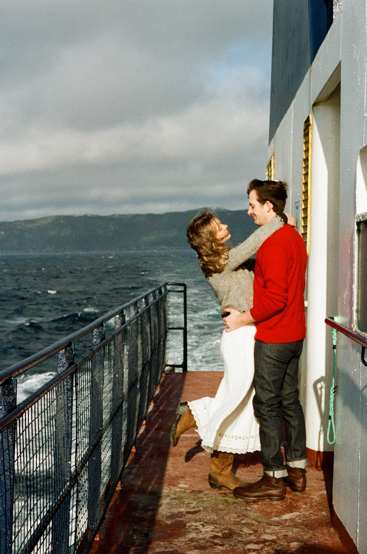 35 mm film photo of bride and groom embracing on the Vancouver Island Ferry during their elopement. Both wear nordic sweaters.