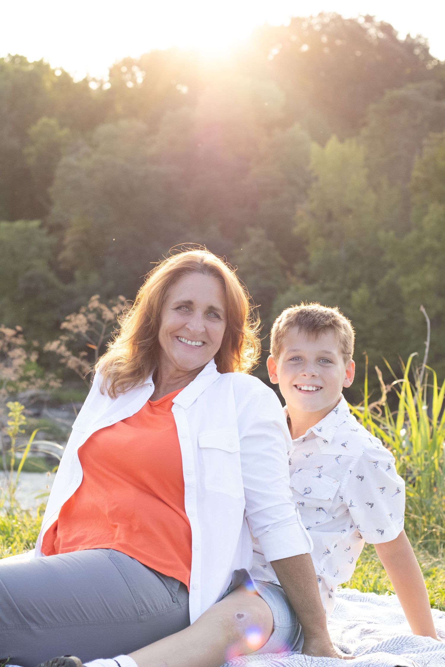 A family enjoys a warm sunset moment together while relaxing in the grass outdoors.