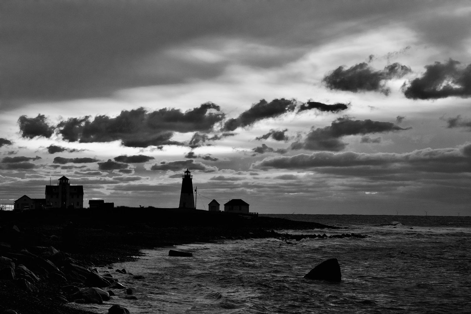 Dramatic coastal landscape featuring a lighthouse silhouette against stormy skies.