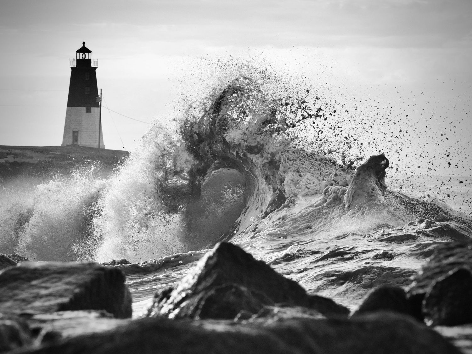 Powerful ocean waves slam into a lighthouse creating spectacular water spray patterns.