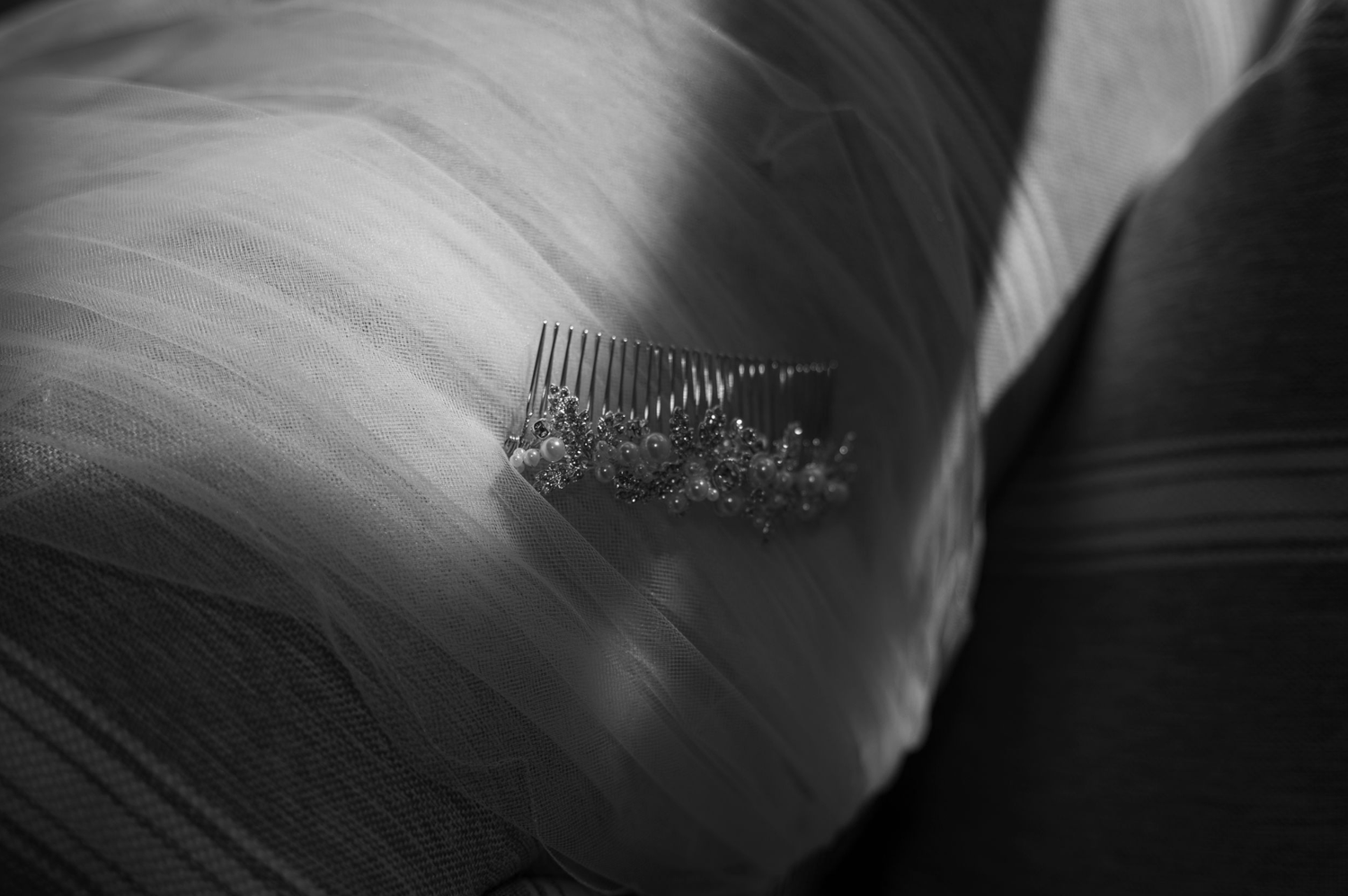 Black and white Detail image showing brides hair piece on top of her veil.  With grainy texture and moody light patterns