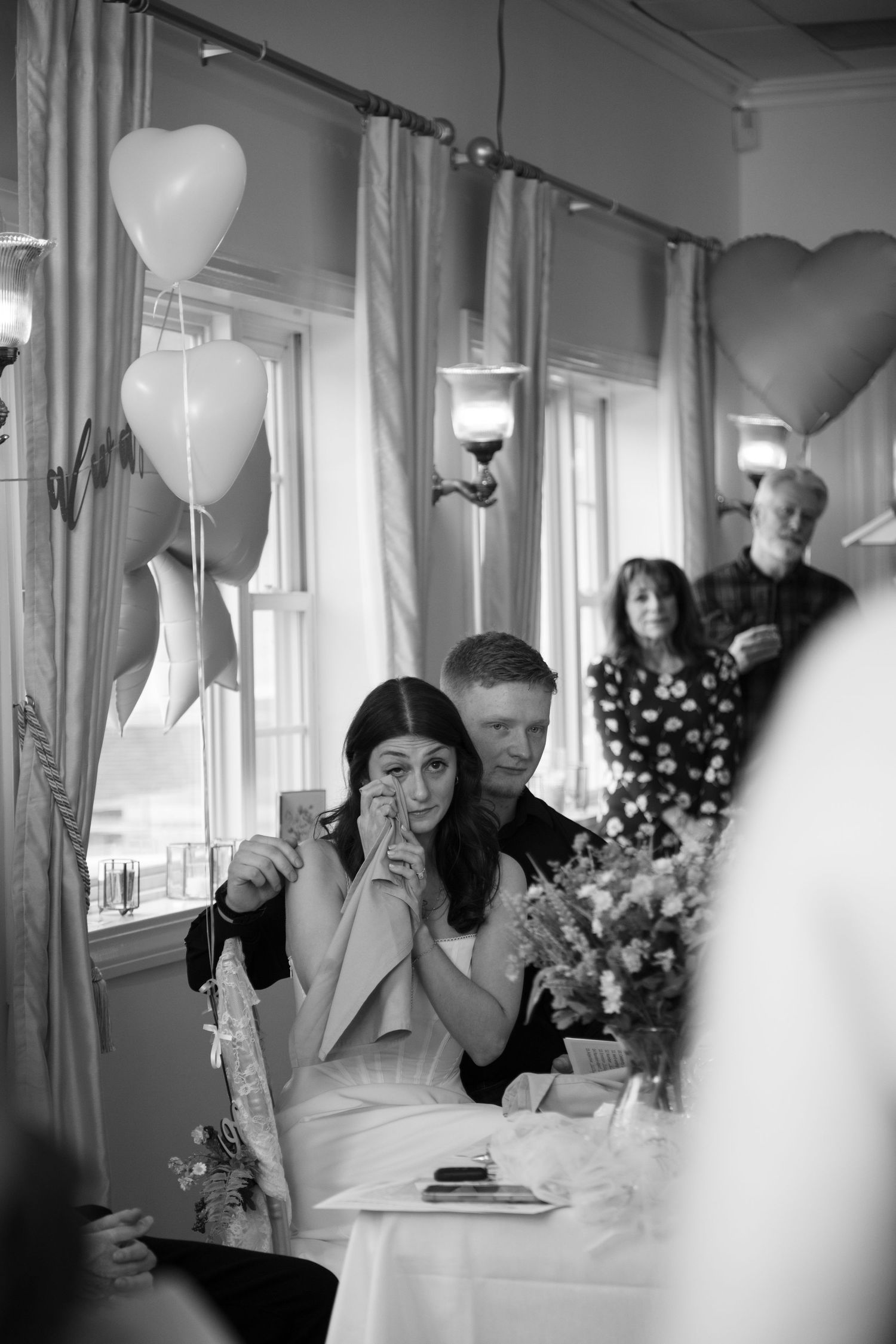 Black and white photos show guests enjoying a celebration at an elegant restaurant with white balloons and decor.
