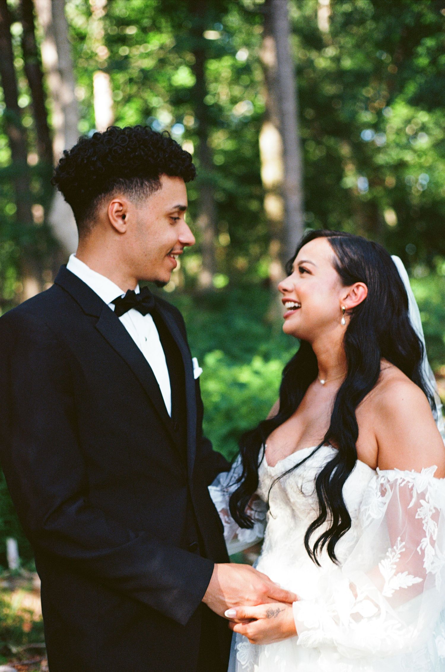 A joyful couple shares a candid moment together in the woods during their wedding celebration. Color Film.