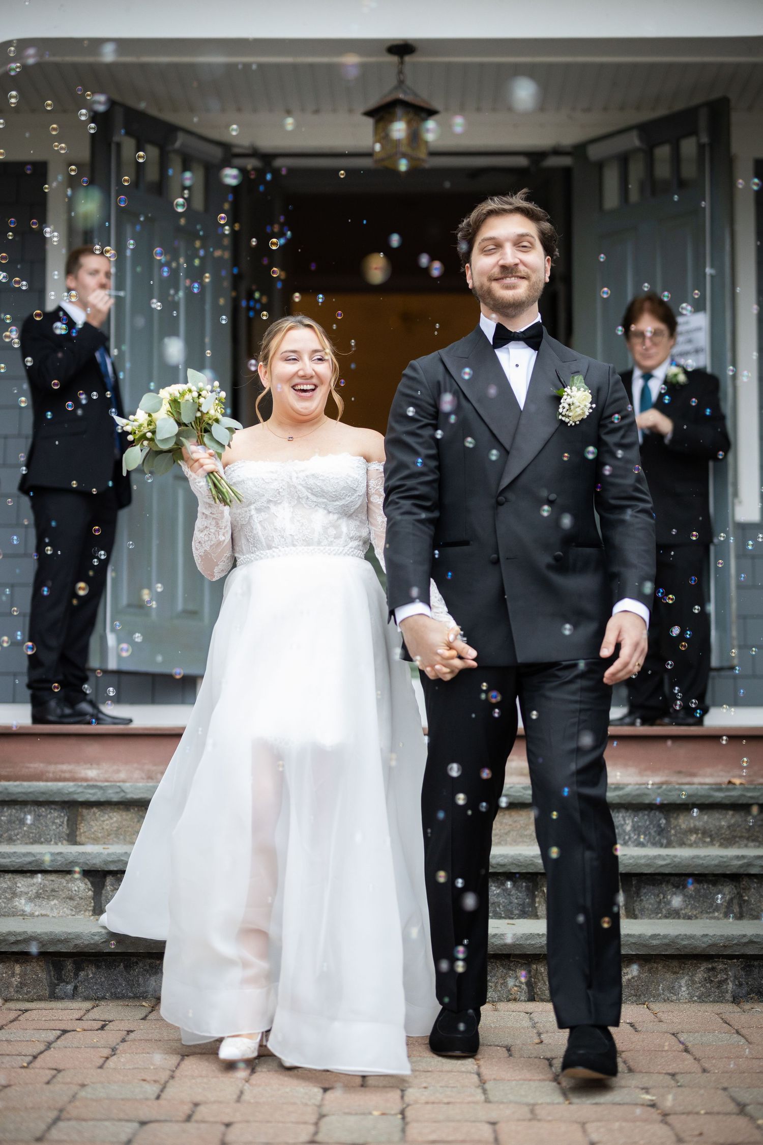 A happy couple shares joyful moments during their wedding celebration as bubbles float through the air. Private church Ceremony.