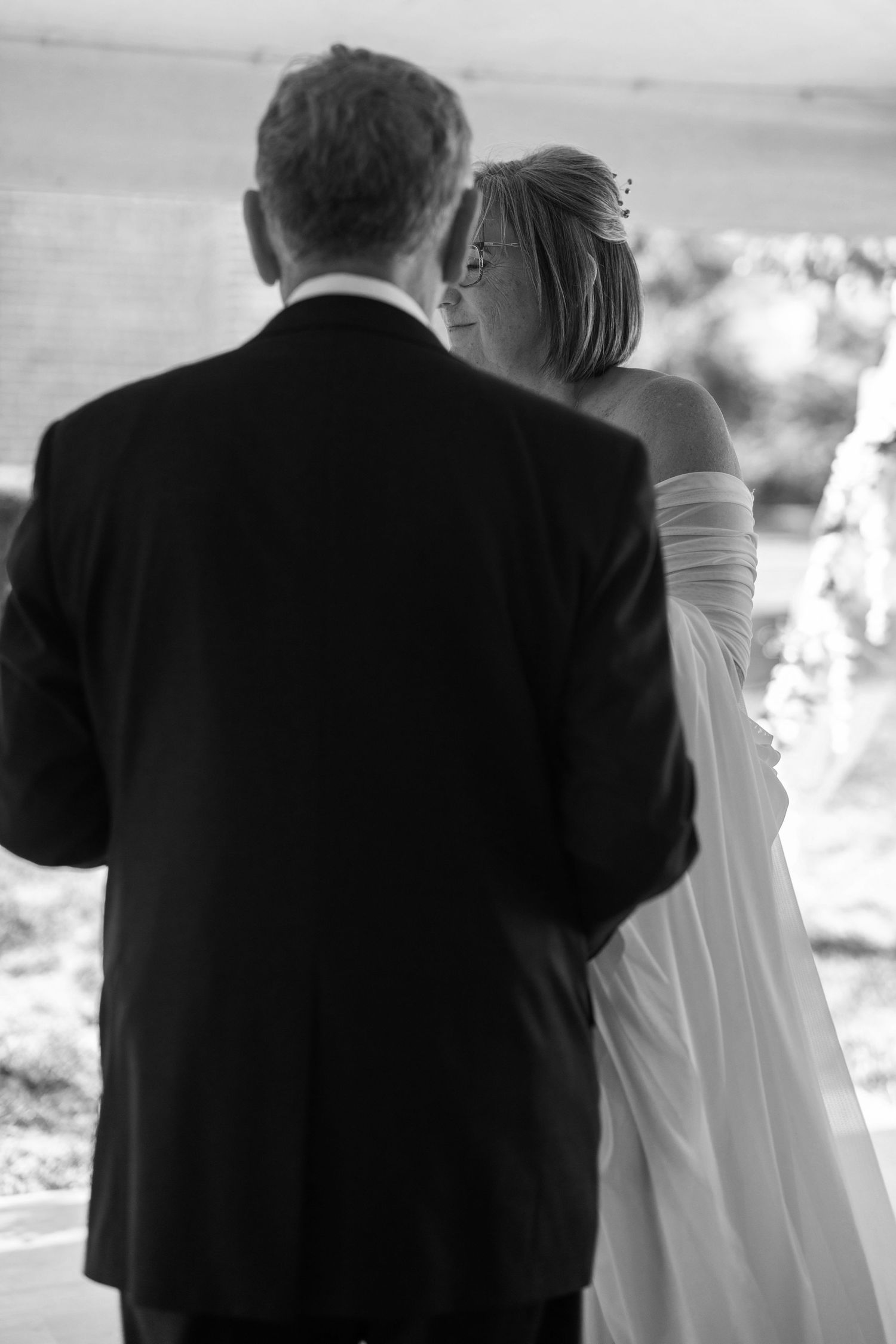 A black and white photo series shows a couple in formal attire standing together and looking at something in the distance.