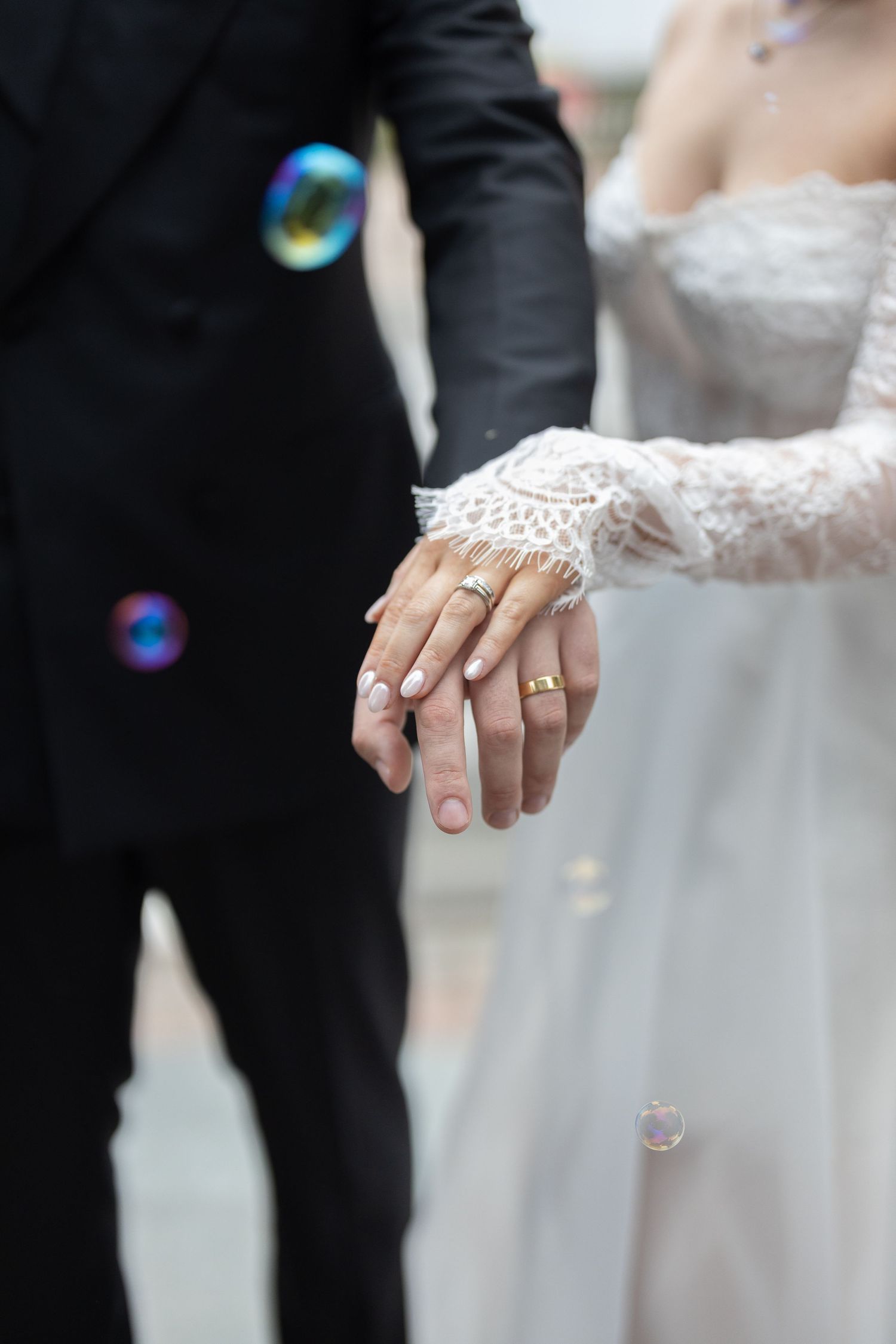 Close-up detail shots of wedding rings and lace dress sleeves during an outdoor ceremony.