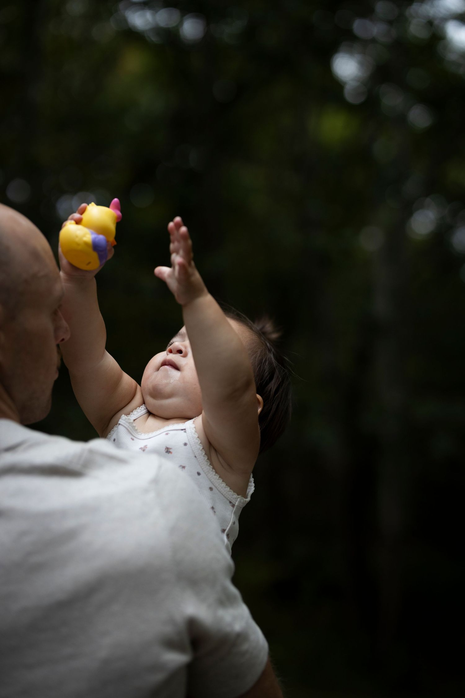 Dad holds baby in moody light while she holds a yellow rubber duck. Twin Brooks Park, Trumbull Connecticut.