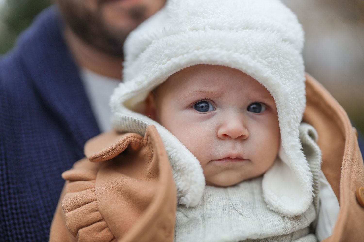 baby wearing a cozy white winter hat looking at the camera with curious expressions.
