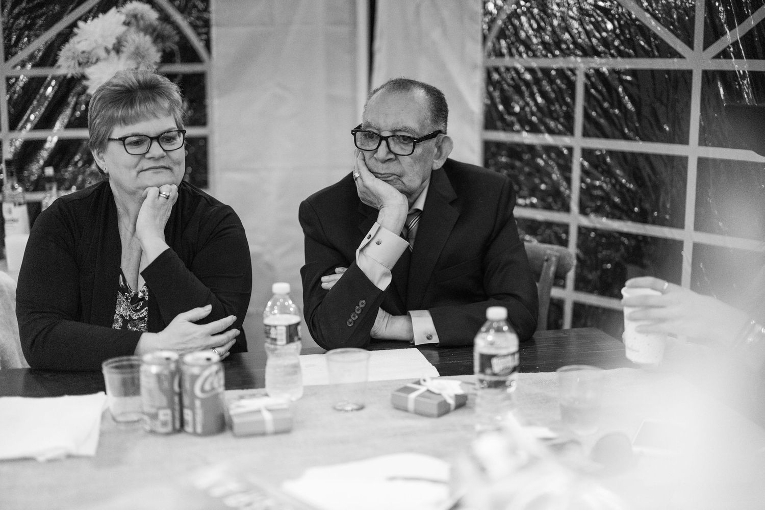 A series of black and white photos showing people seated at a table in conversation.