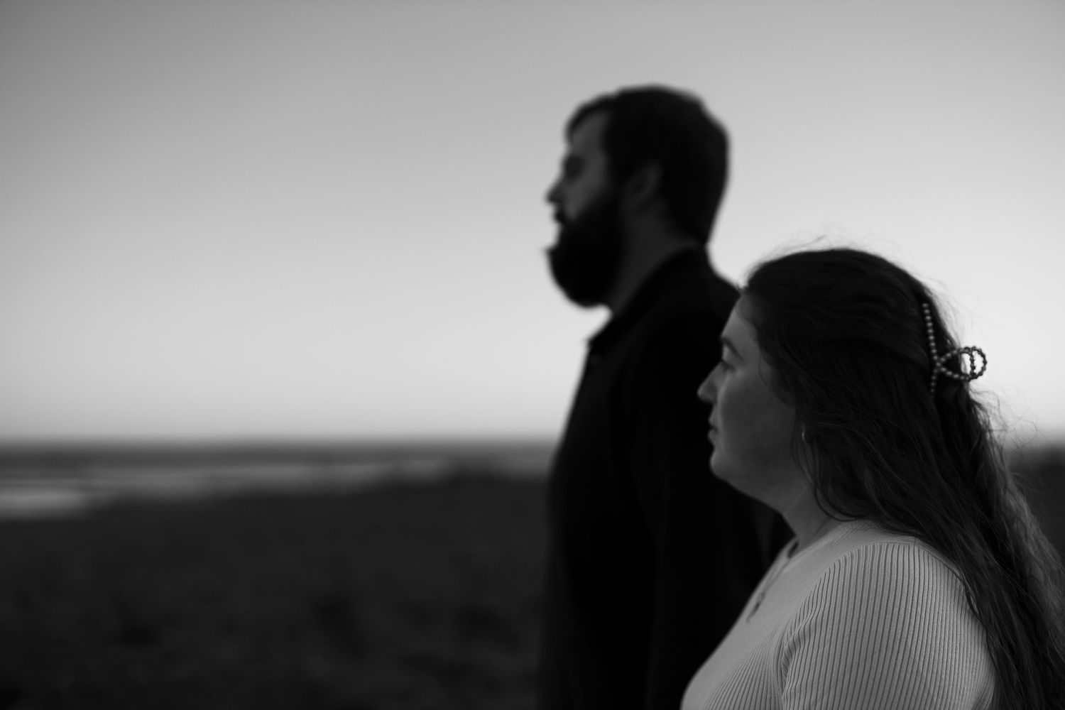 Silhouetted couple embraces against a dramatic sunset sky on a beach.