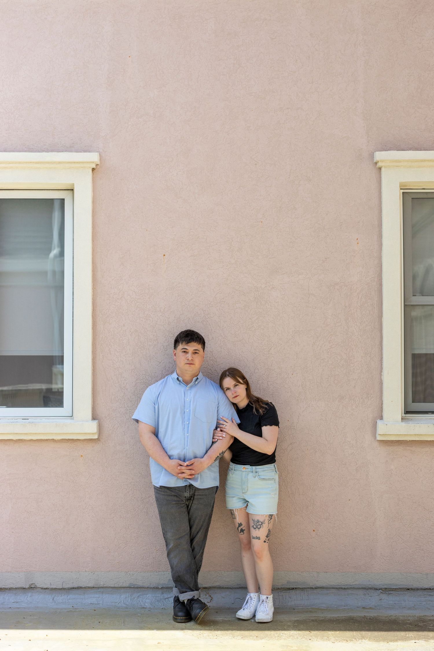two people posing against a beige wall, creating a minimalist artistic composition. Film portrait. engagement session
