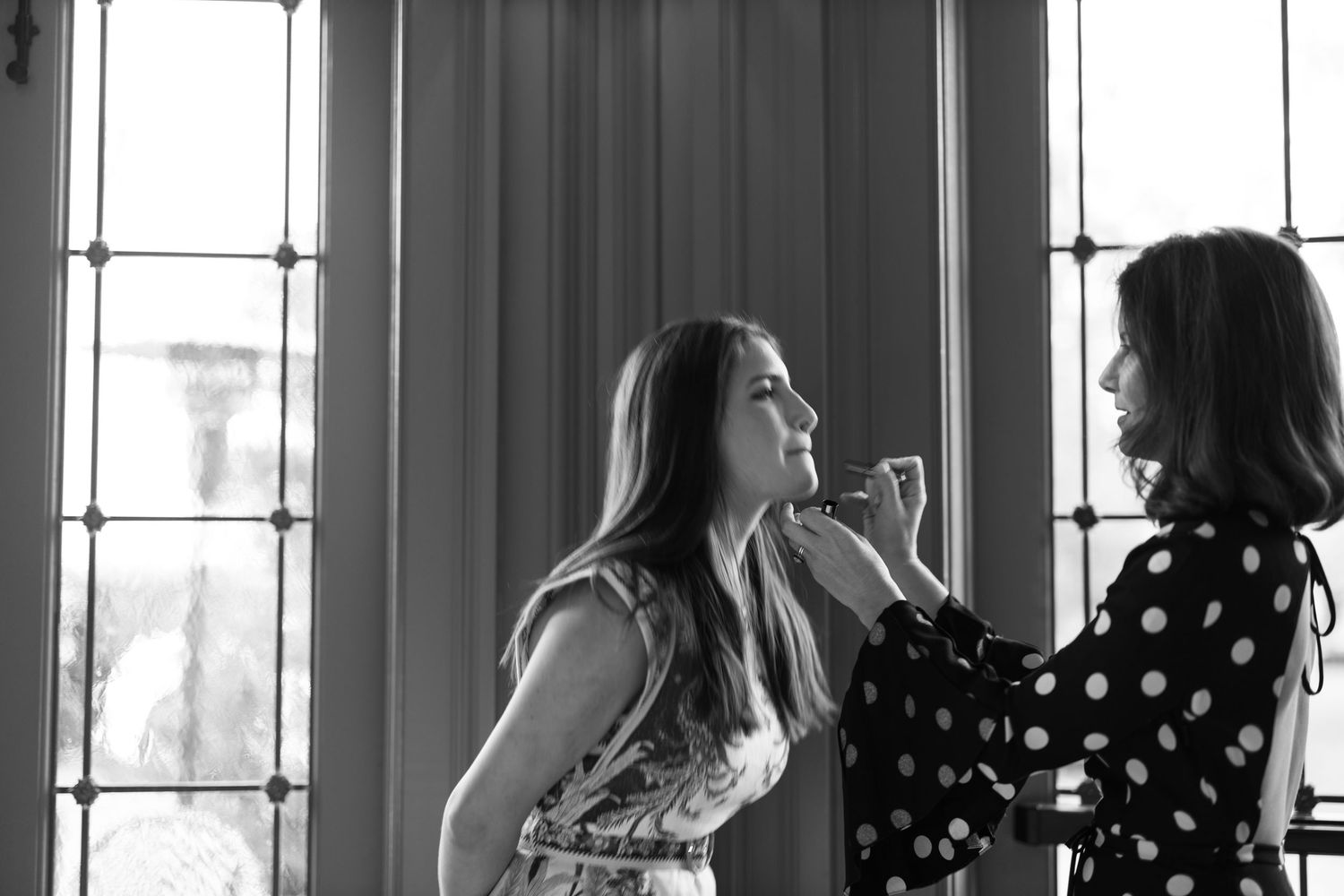 Black and white photo showing silhouettes of people against bright windows in an elegant interior space.