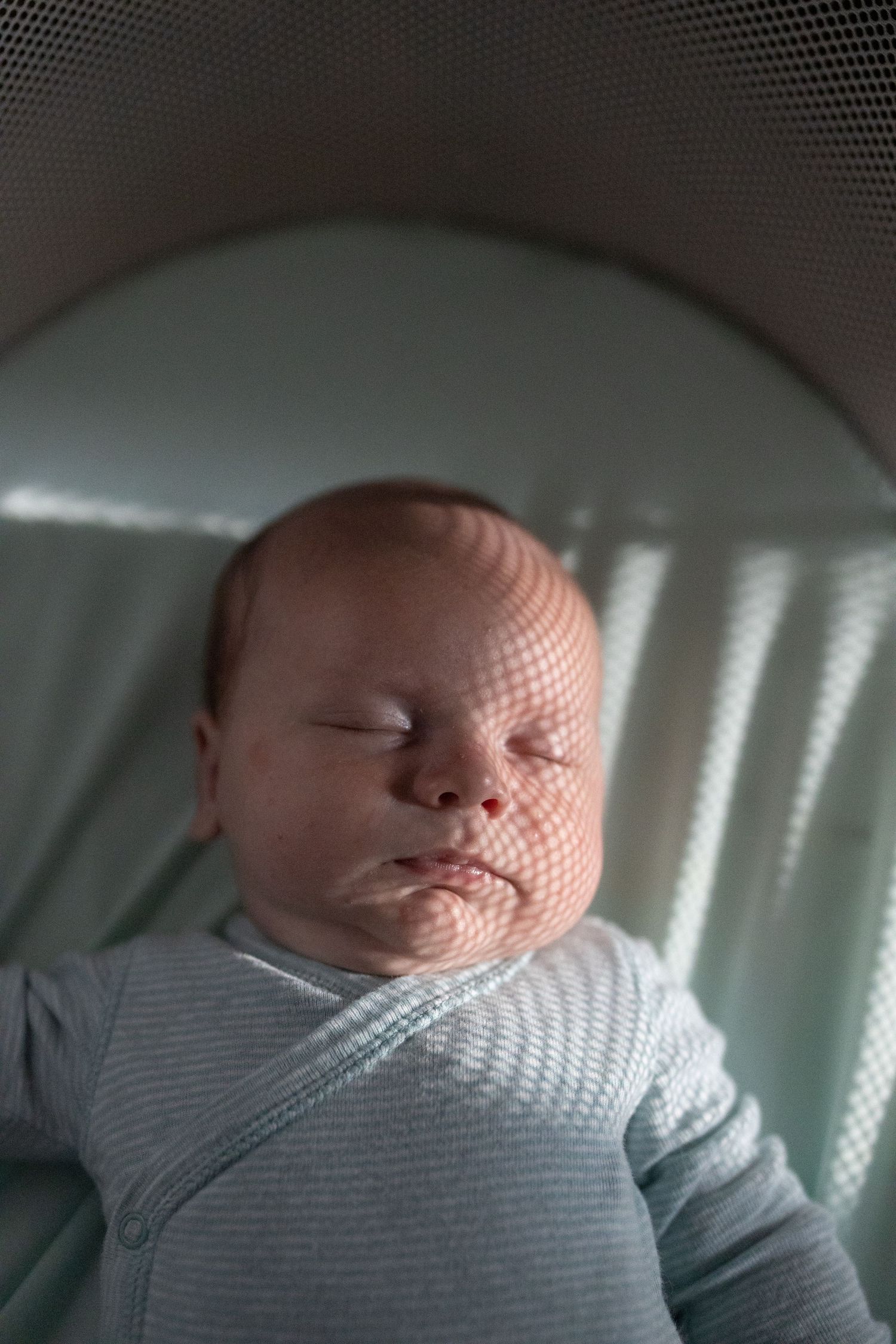 Creative portrait of a newborn with moody light patterns on his face.