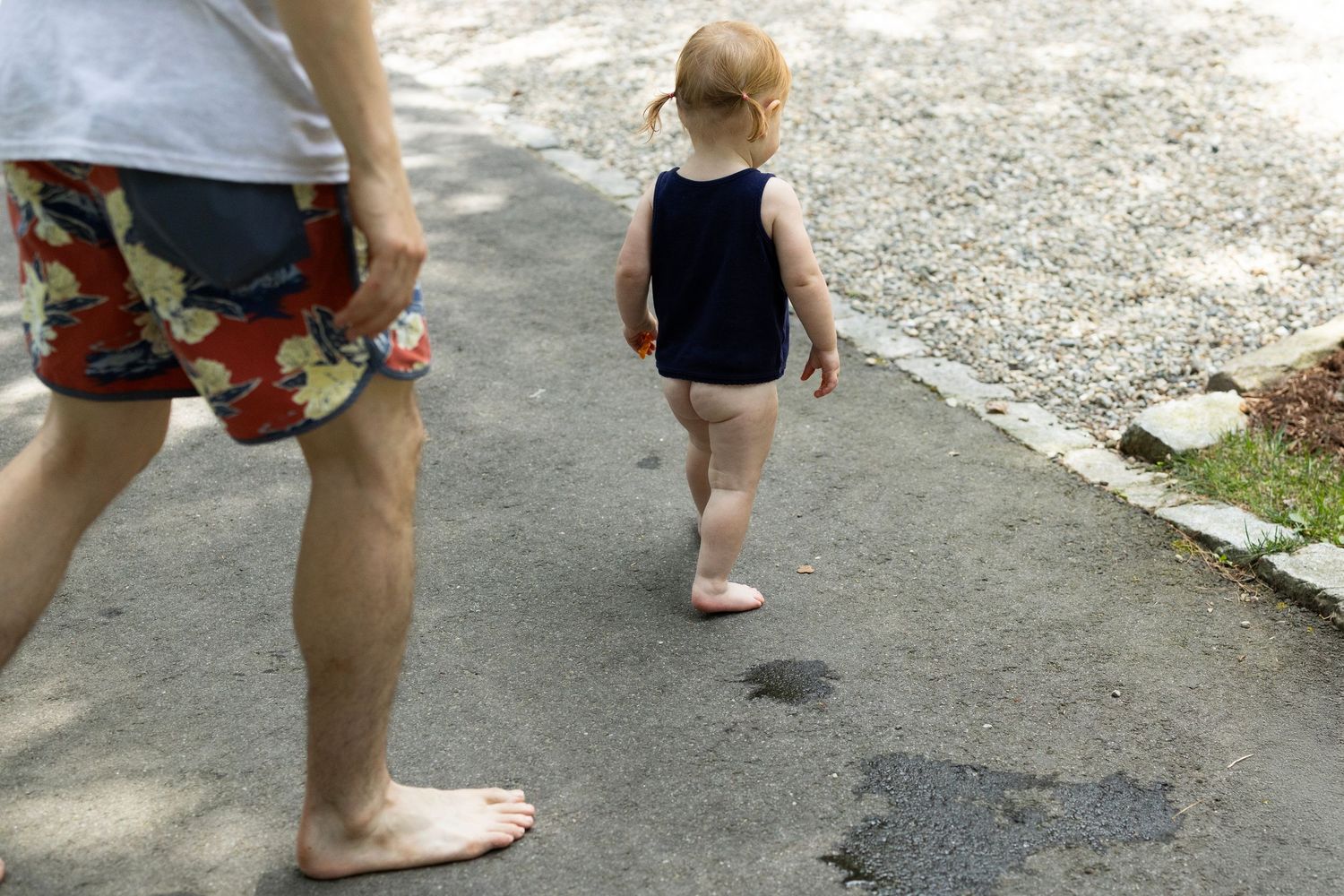 A close-up view of toddlers bare feet and bare bottom. He's walking around on the payment.