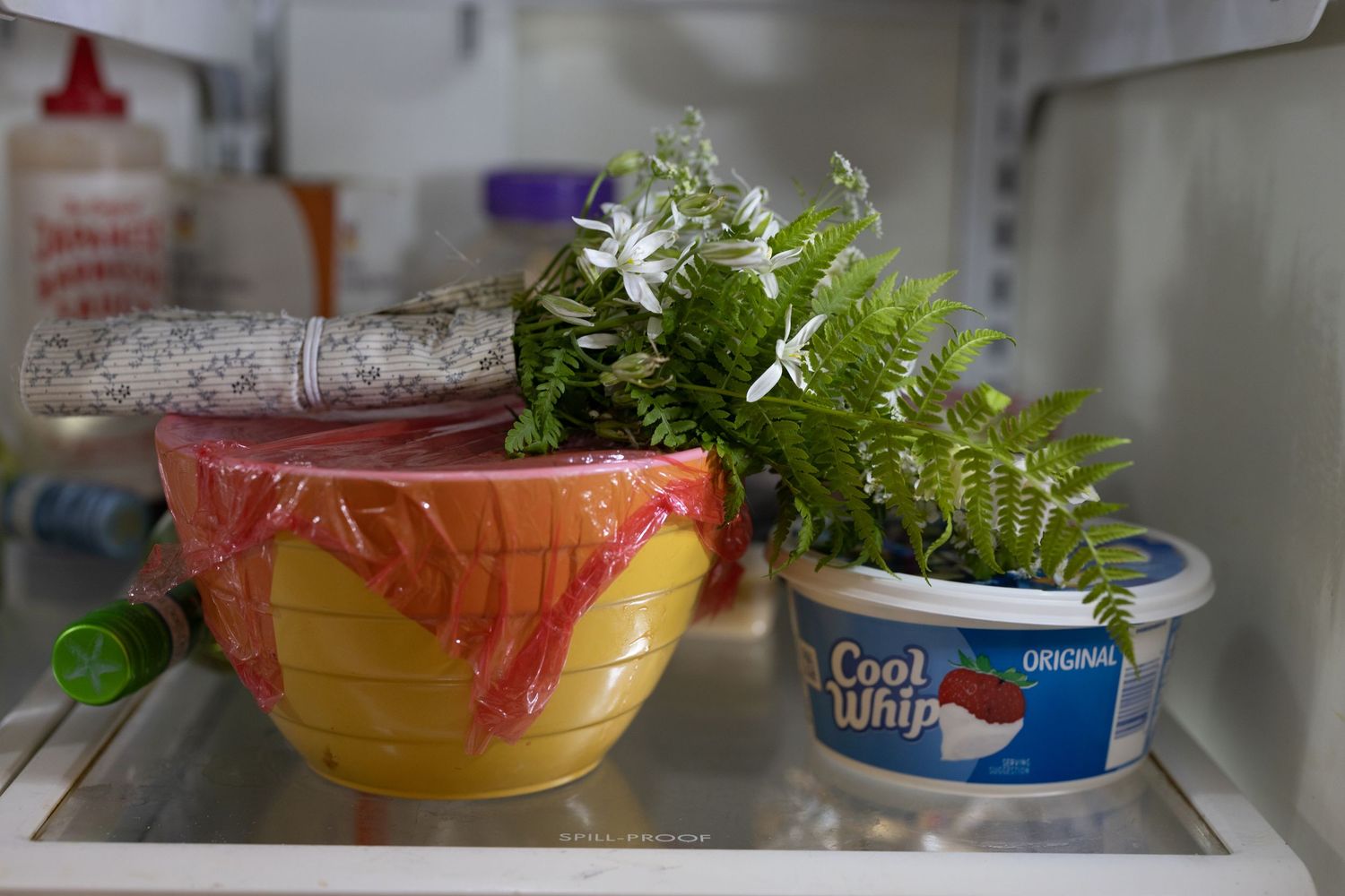 Wildflower boutique placed inside refrigerator shelf next to cool whip container.