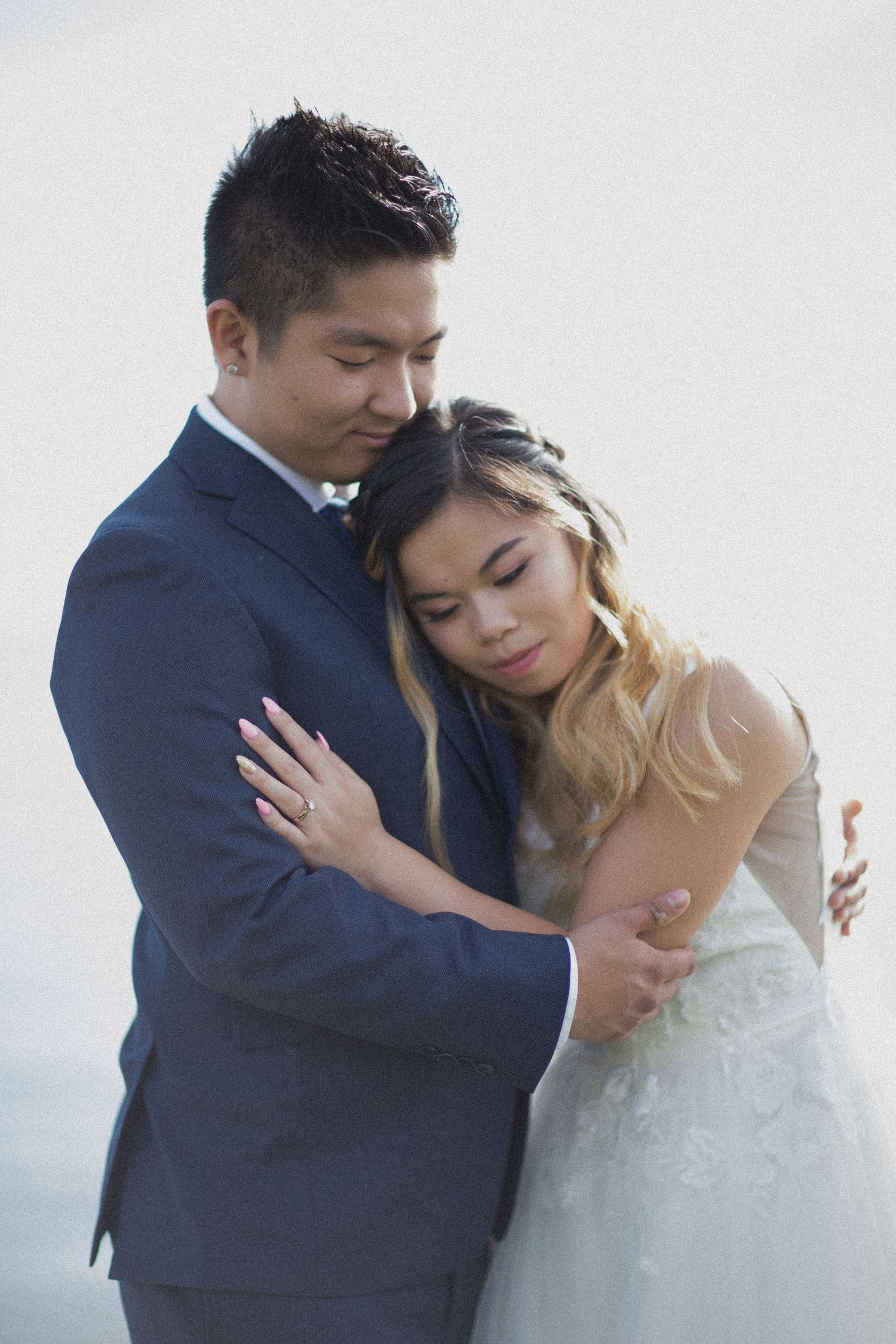A couple in wedding attire embrace tenderly in a series of romantic portrait poses against a light background.