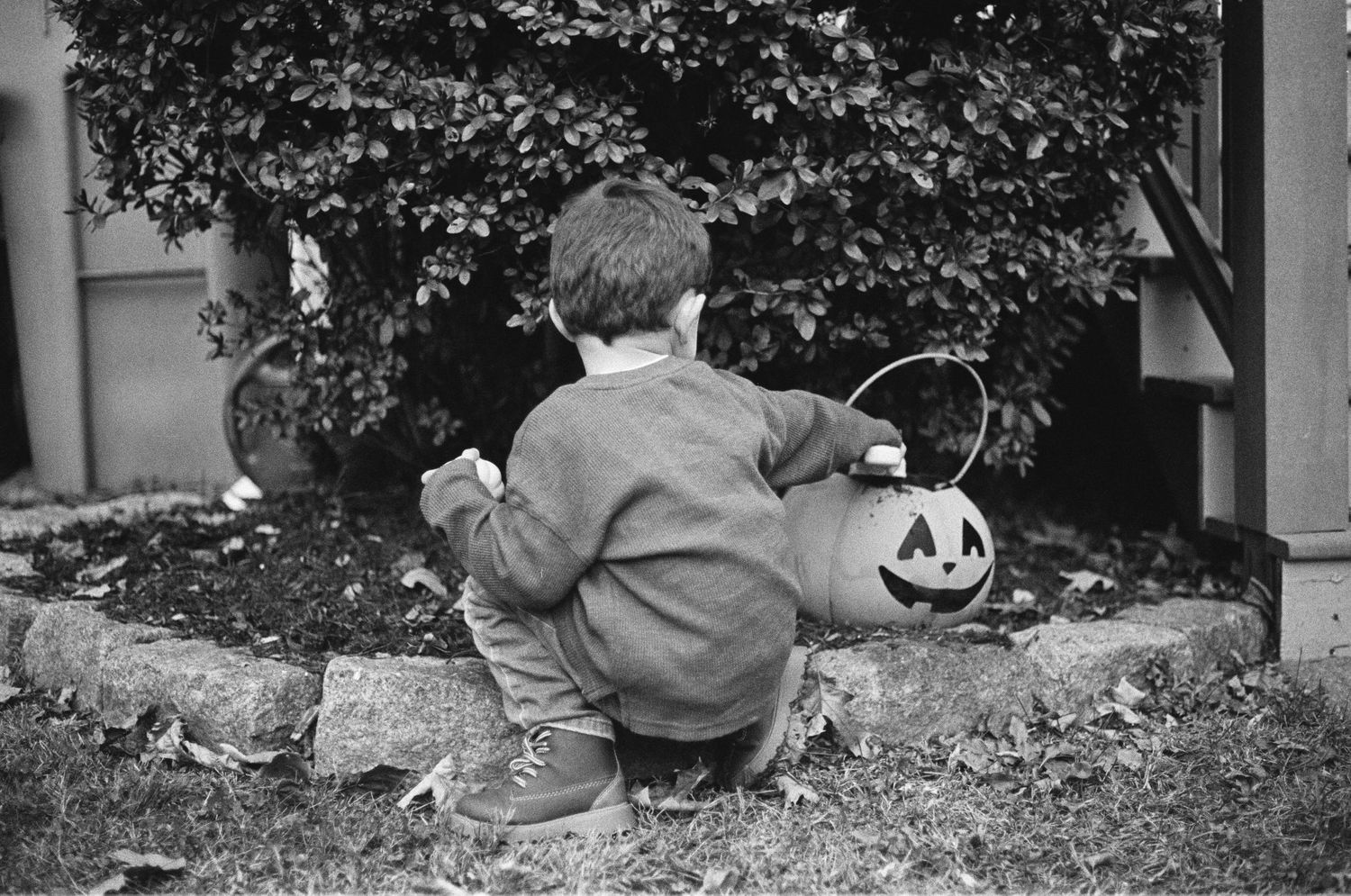 Black and White Film Portrait of Child playing with a pumpkin Basket.