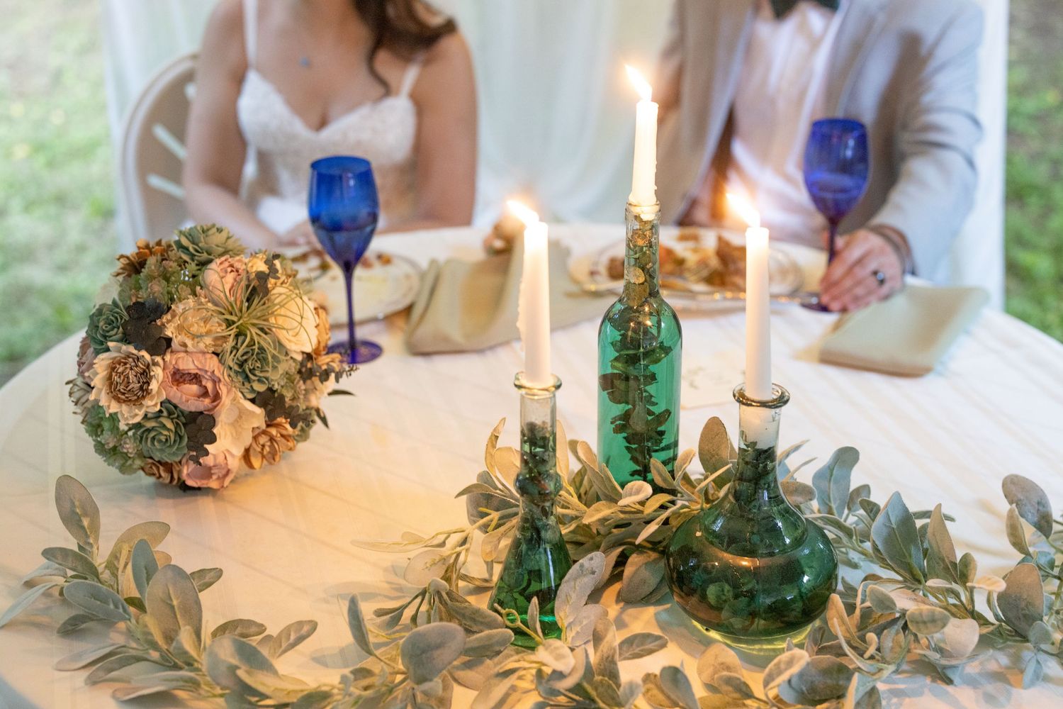 A romantic wedding tablescape with glowing candles, delicate florals, and elegant place settings in soft neutral tones.