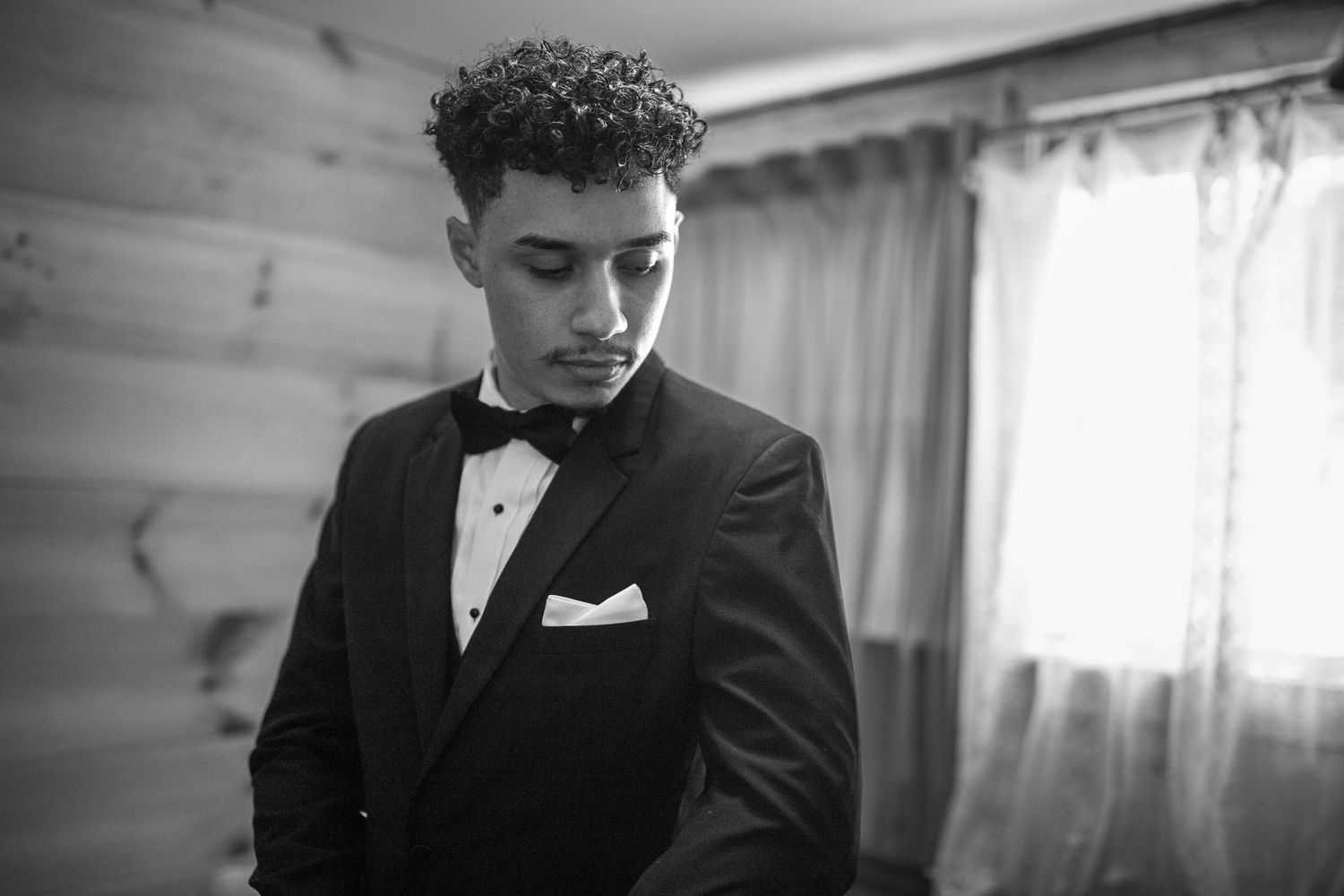Black and white portrait of a groom getting ready. Looking down
