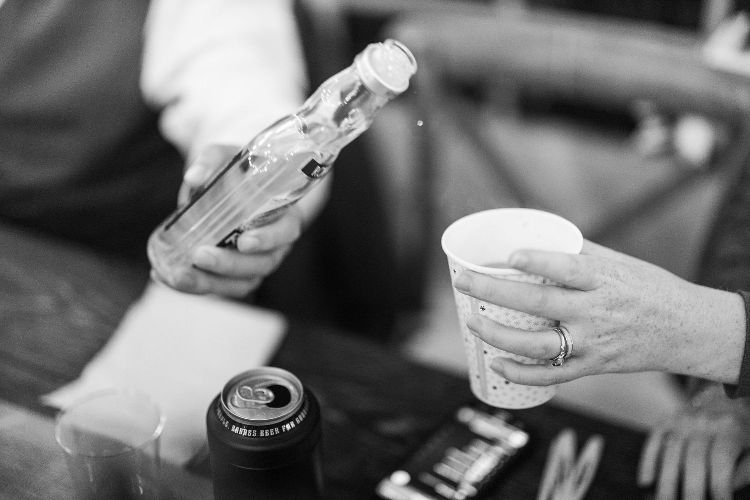 Black and white image of hands holding sambuca pouring pour it into a coffee  cup. Backyard wedding.