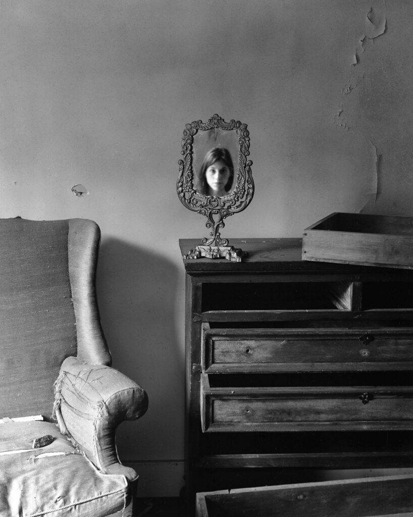 black and white film portrait of antique mirror with reflection of a girl inside an Abandoned house