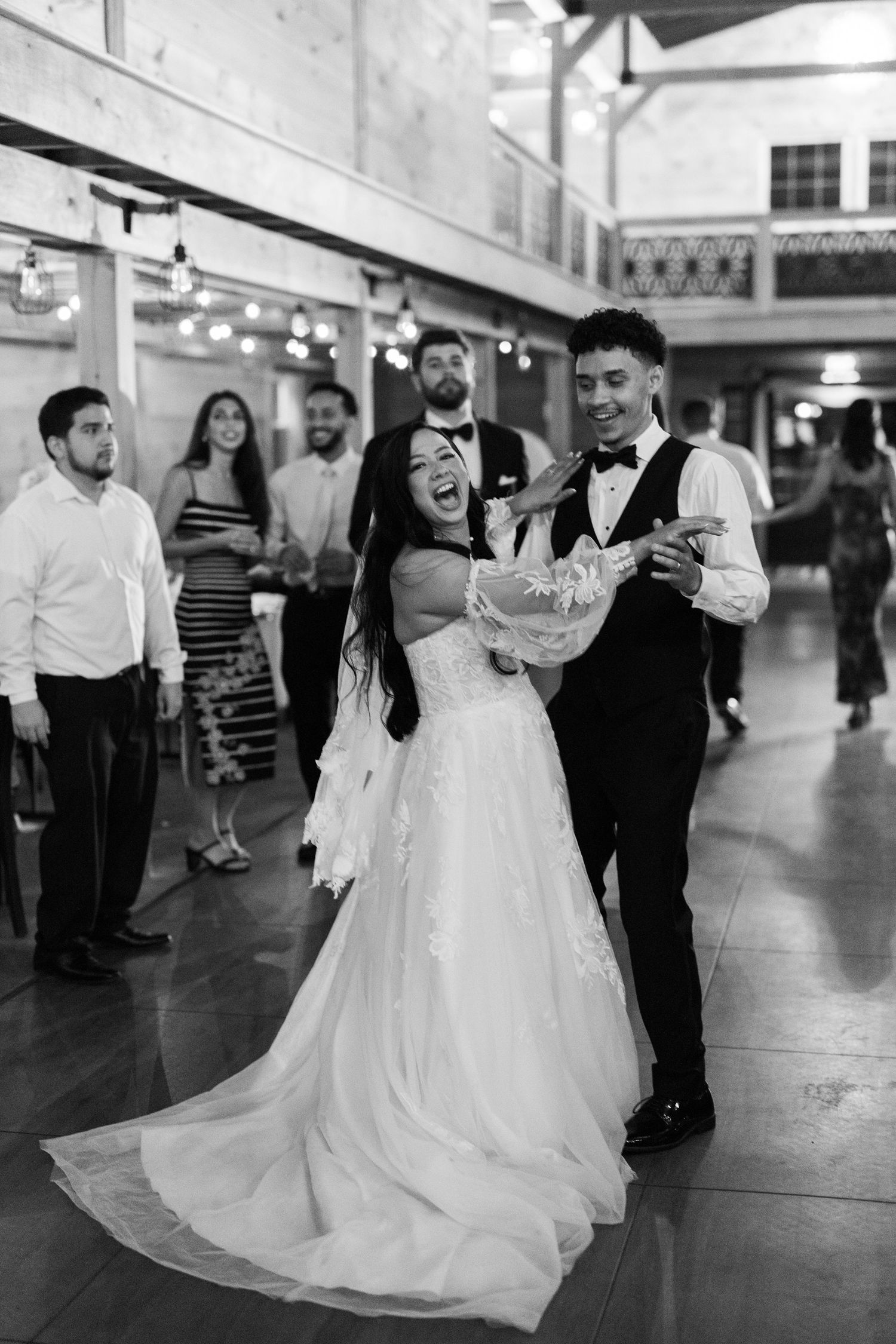 A couple dances together at their wedding reception, with the bride wearing a flowing white ballgown.