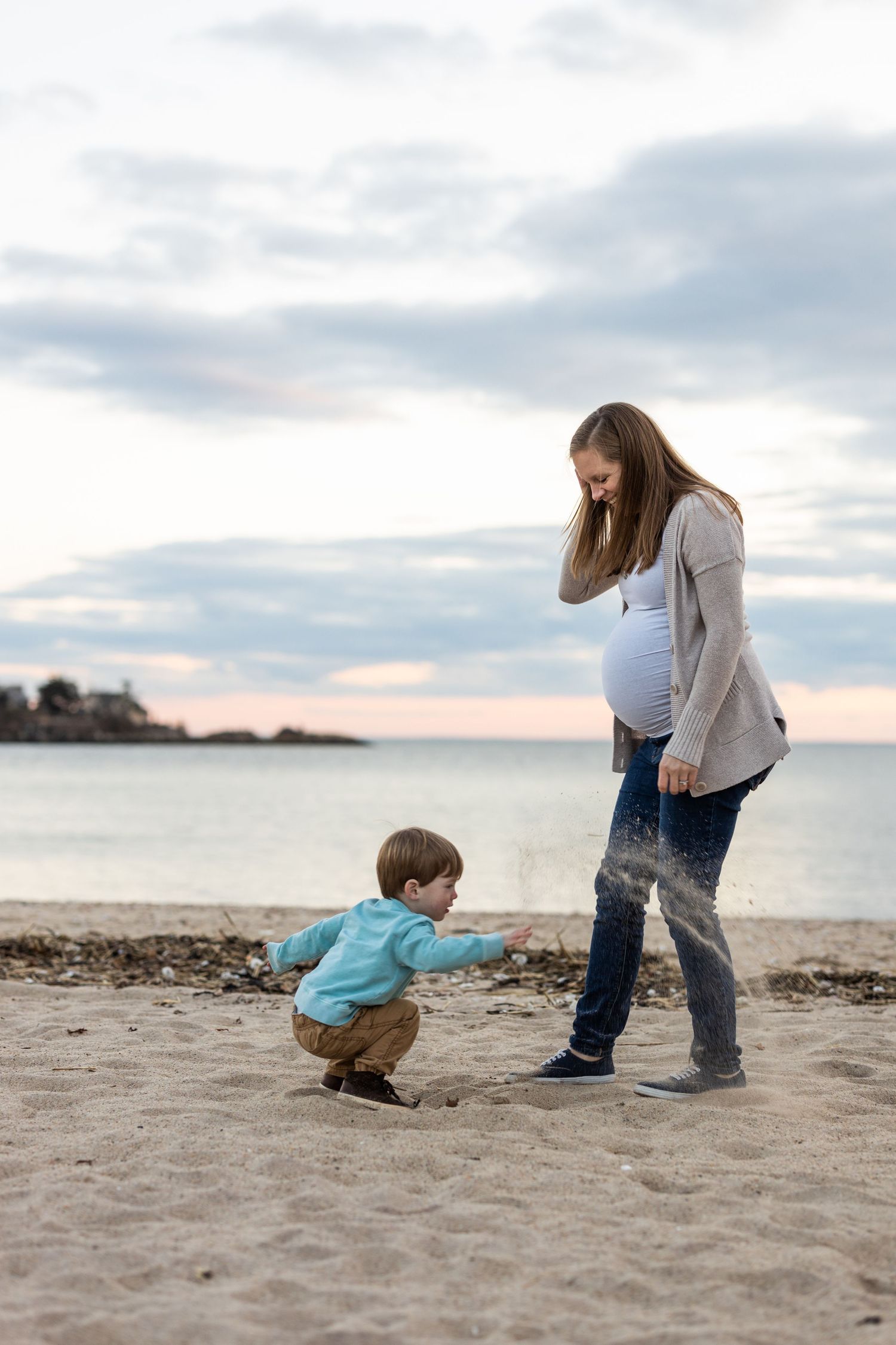 Child Throws sand at beach. Sunset family portraits.
