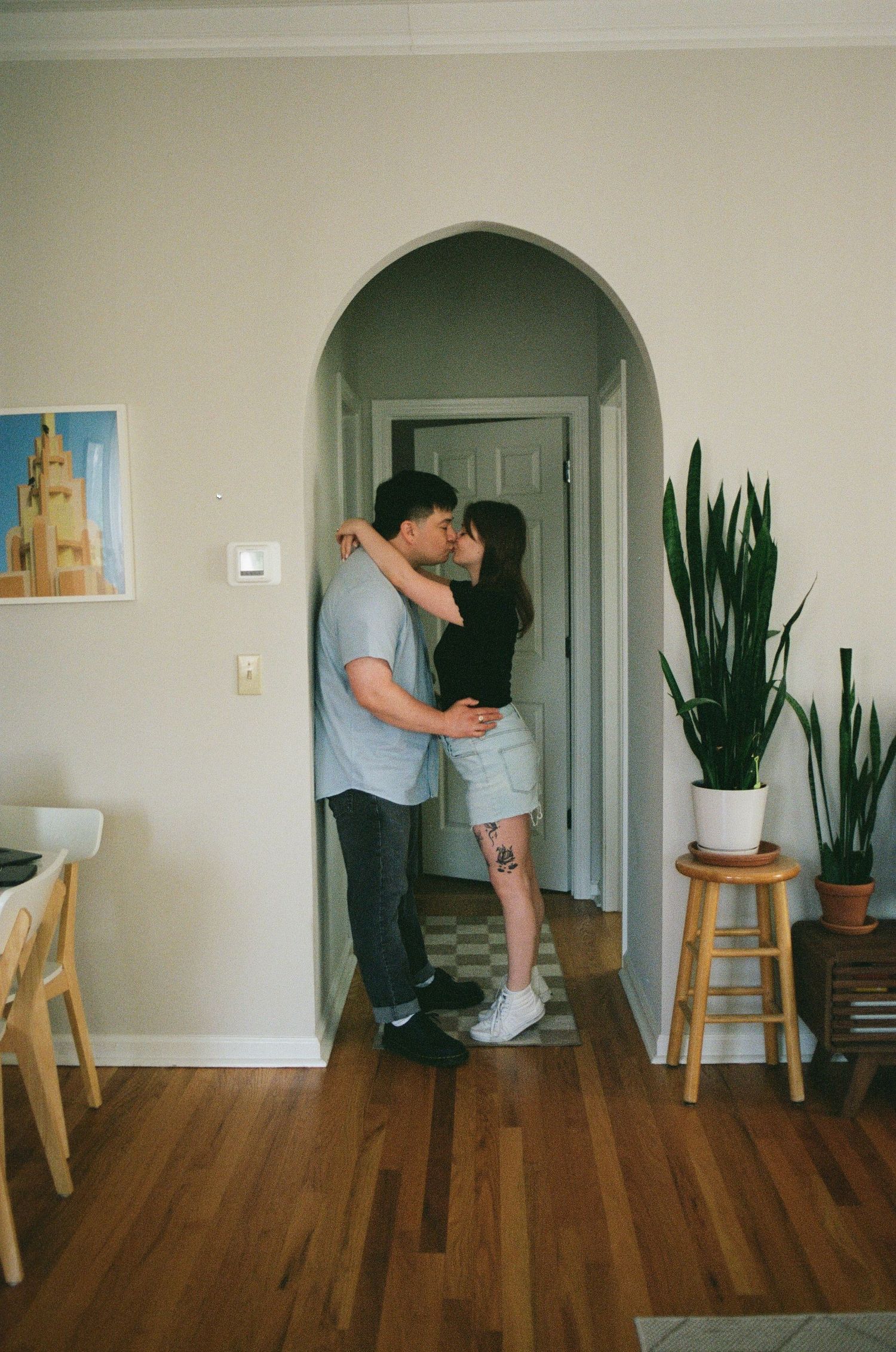 Film portrait of a couple kissing inside an apartment  archway during engagement session