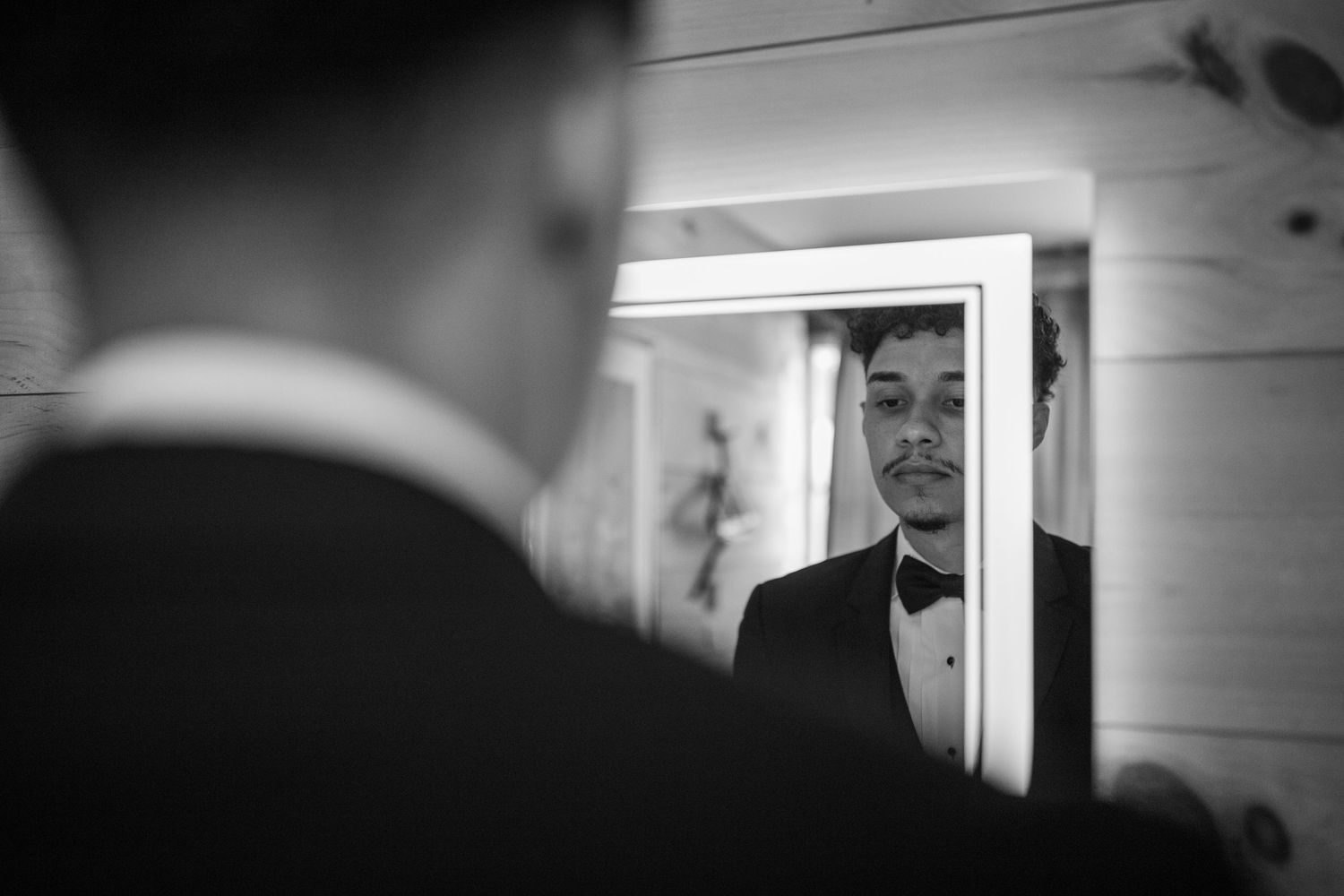 Black and white portrait of groom getting married through a mirror. Portrait is of groom's reflection.