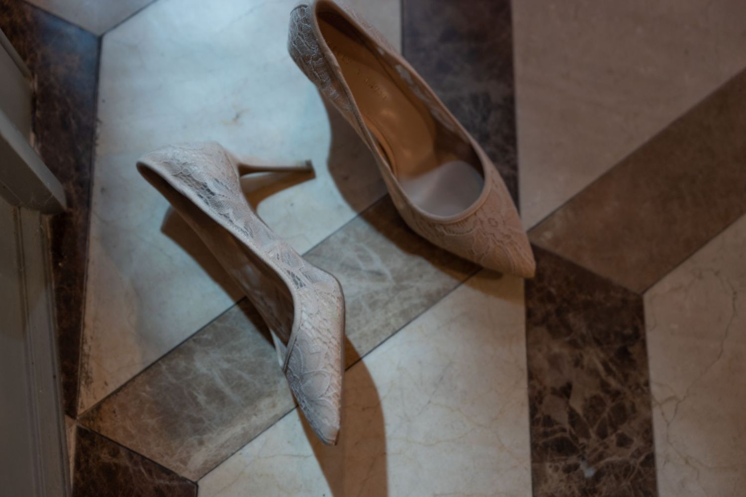 Closeup view of a brown leather high heel shoe on a reflective surface with dramatic lighting.