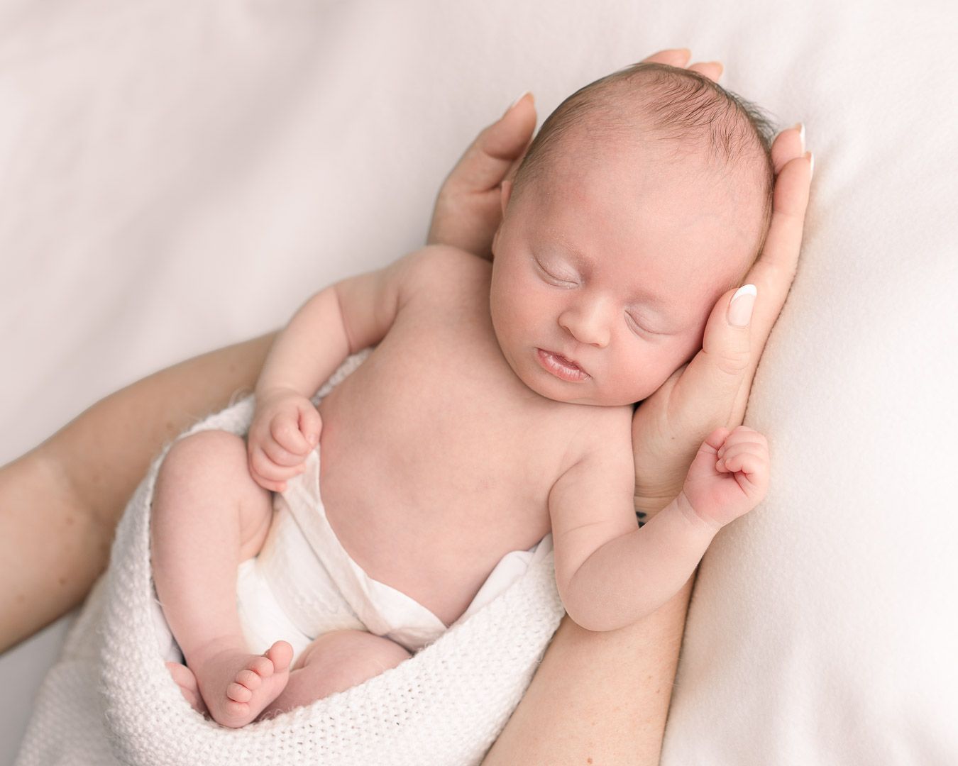 Newborn Baby photographed sleeping on his mother's arms