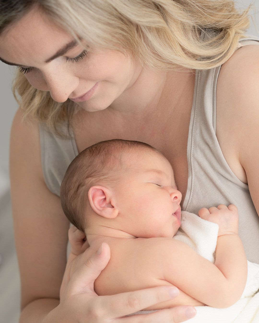 Baby held by her mother during a newborn photo shoot in the comfort of her house by a Chesterfield Newborn photographer.