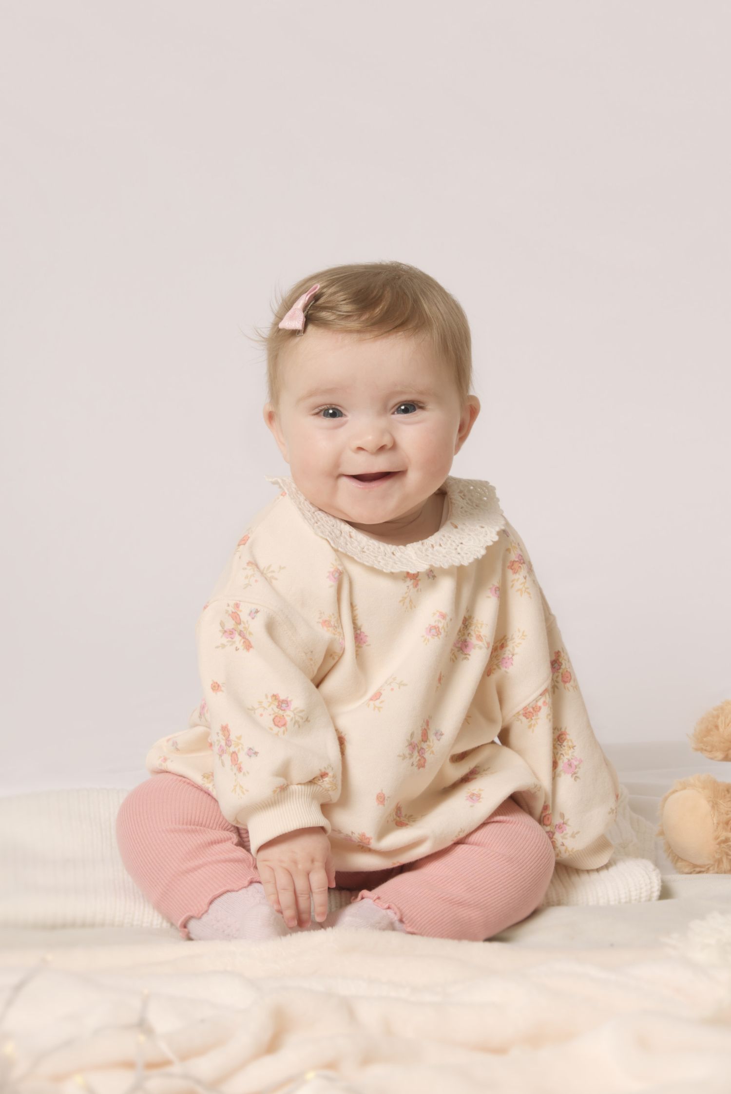 Sitter session portrait of a six-month-old baby smiling in a mobile studio in Dronfield.