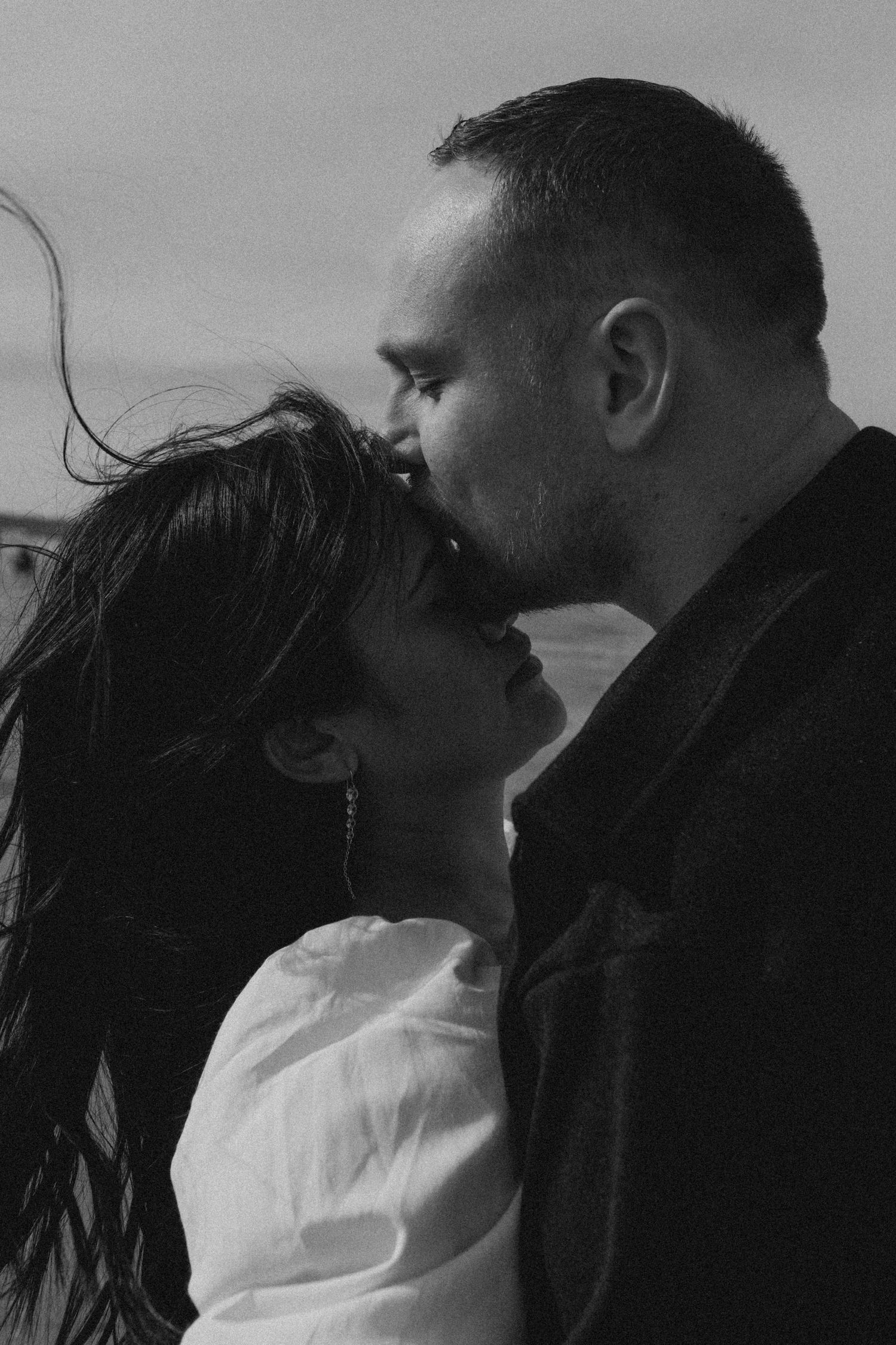 Intimate black and white close-up of a couple about to share a kiss outdoors.