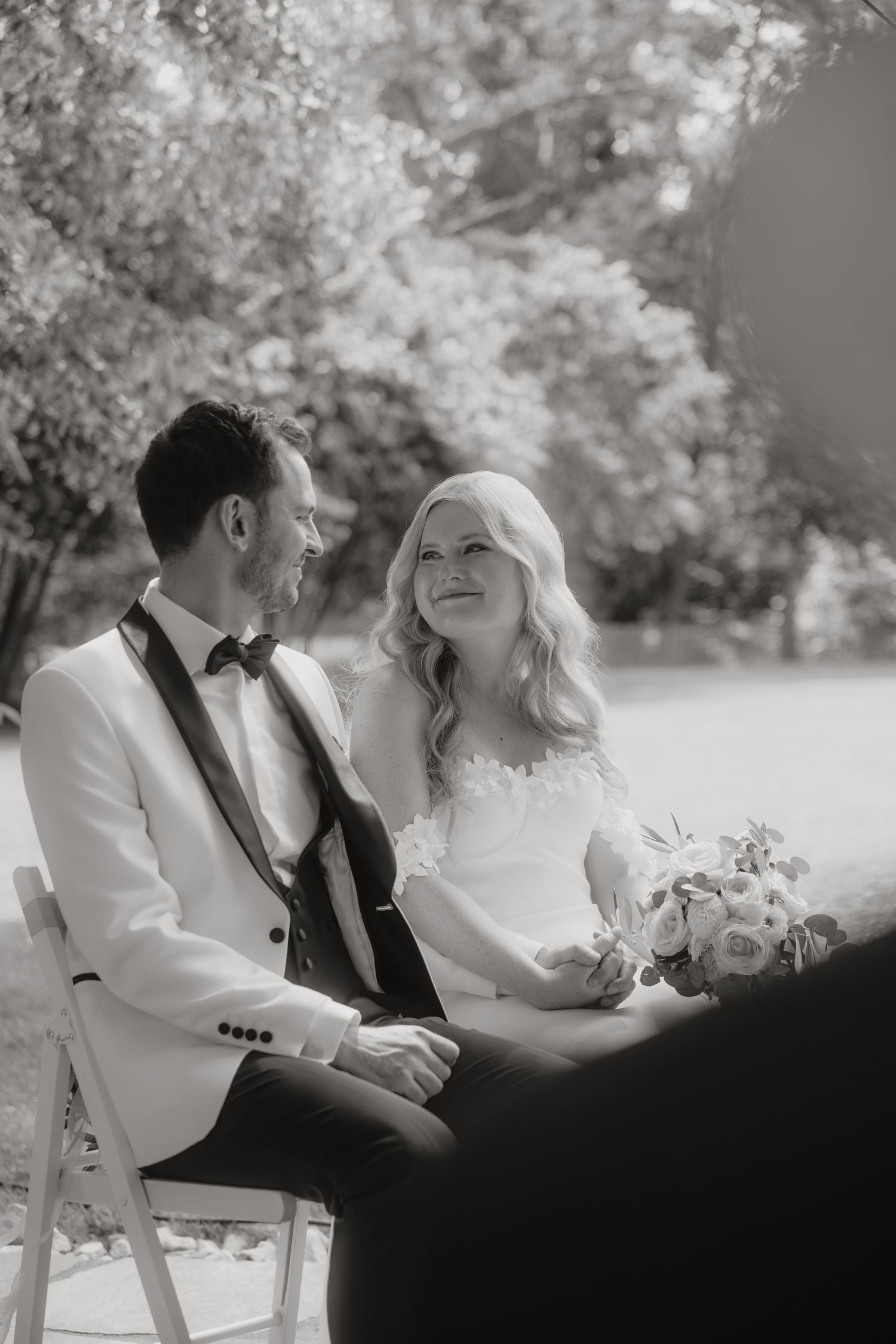 Bride and groom share a tender moment during outdoor wedding ceremony, bride holding bouquet.