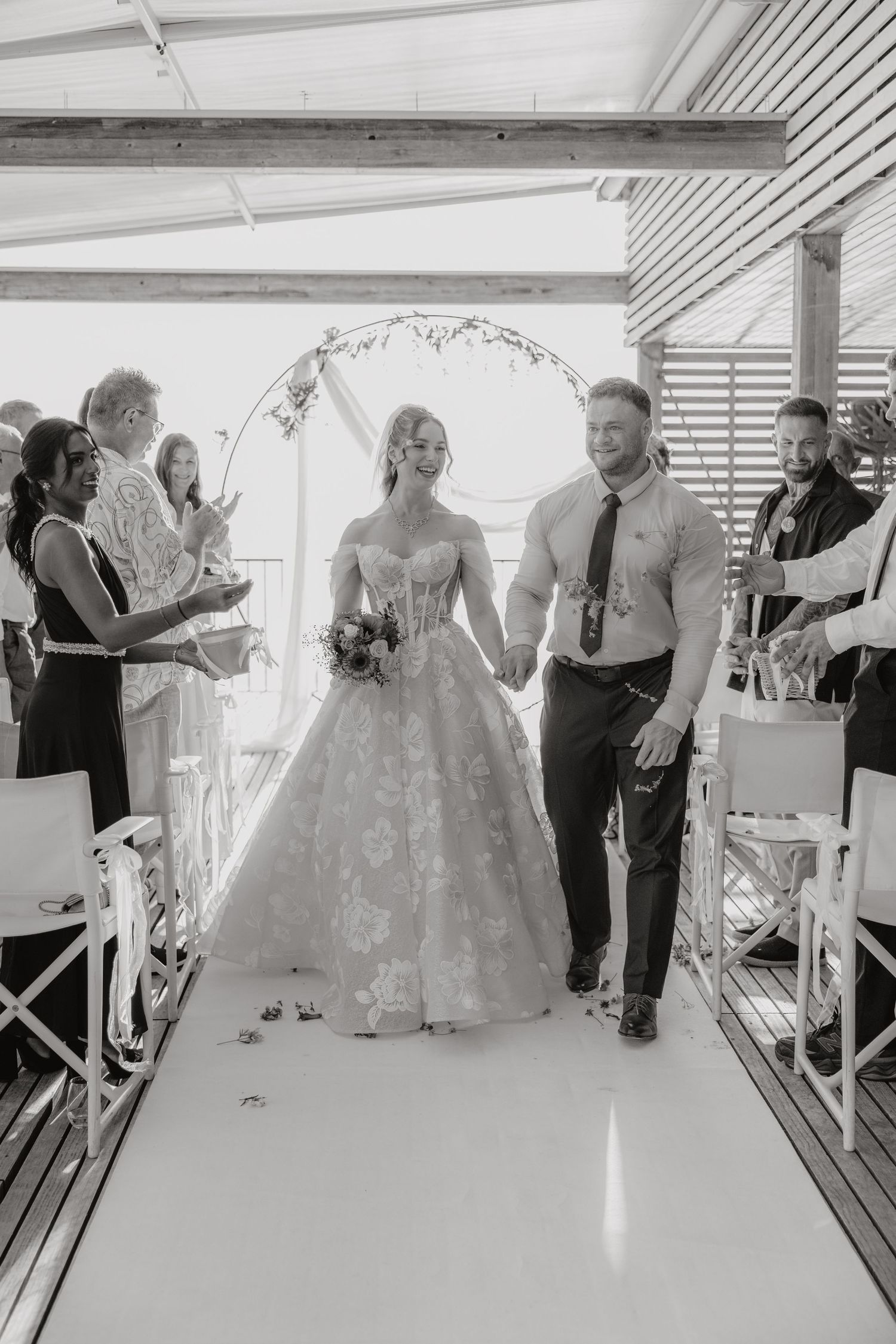 Black and white photo of a bride and groom walking down the aisle at their wedding ceremony.