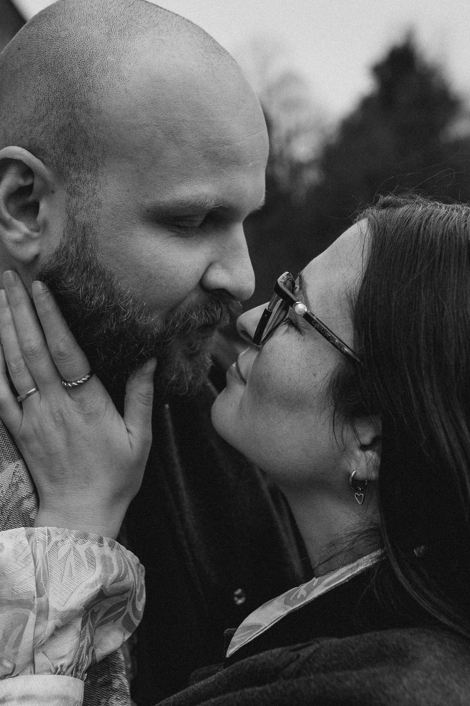 Black and white close-up of a couple about to kiss, groom cradling bride's face tenderly.